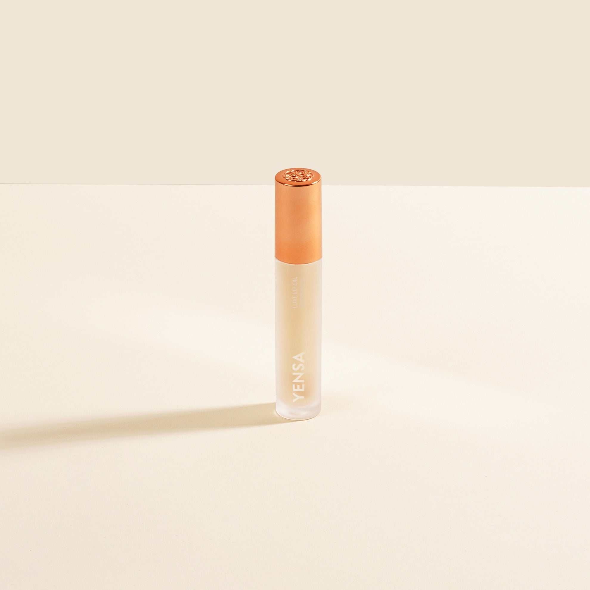 Luxe Lip Nourishing Oil in a clear cylindrical tube with a peach-orange cap and visible warm-toned oil.