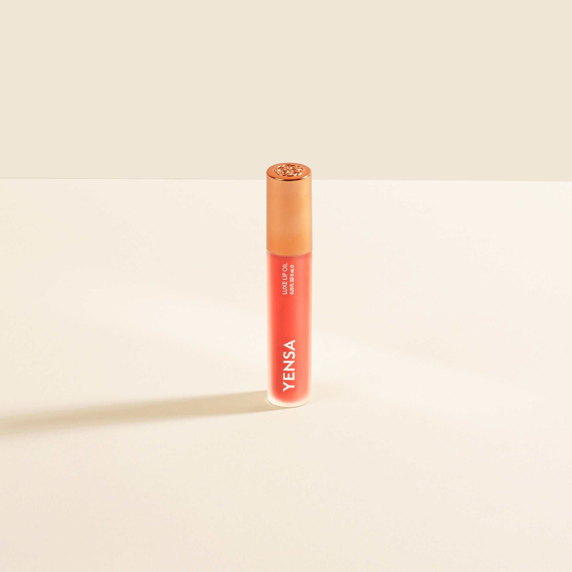 Luxe Lip Nourishing Oil in a slim coral-orange tube with a translucent cap and white vertical branding