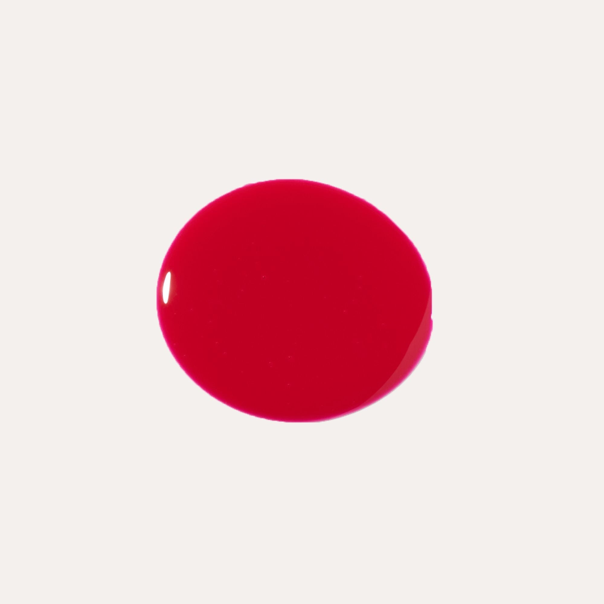 Luxe Lip Nourishing Oil in vivid glossy red, shown as a smooth, rounded swatch of rich tinted lip oil.