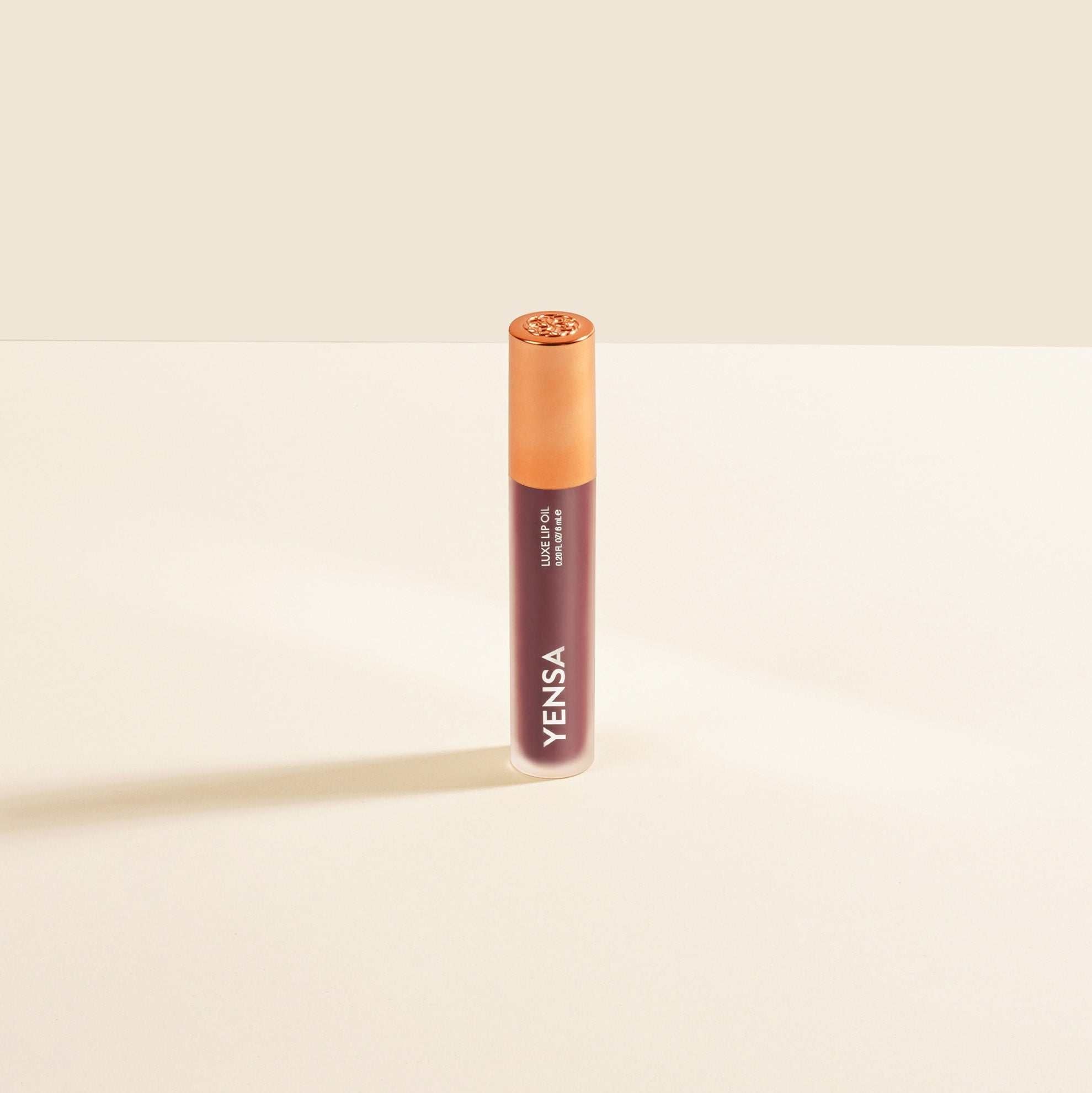 Luxe Lip Nourishing Oil in a slim mauve tube with a translucent peach cap and glossy finish