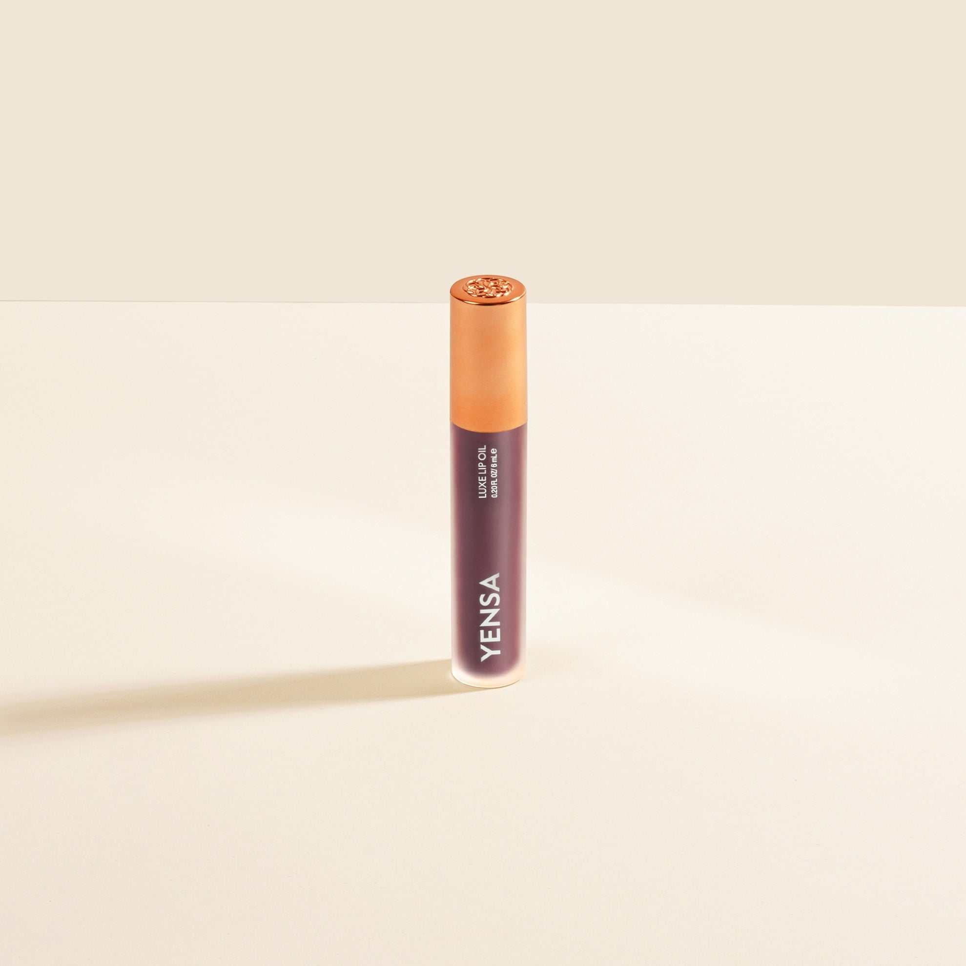 Luxe Lip Nourishing Oil in a slim mauve tube with a warm peach cap and glossy gold-toned top