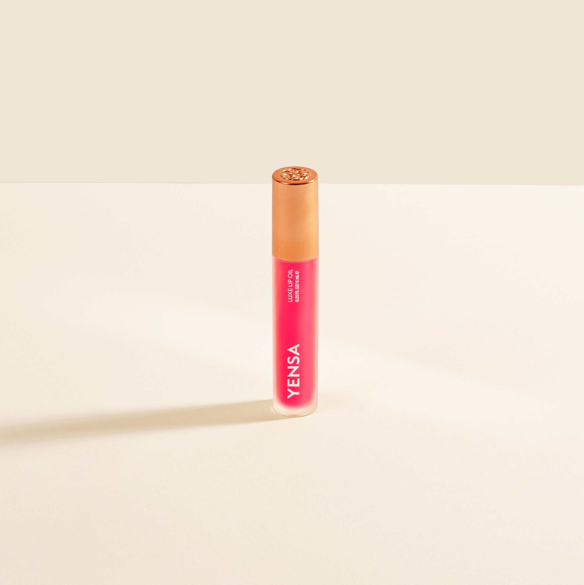 Luxe Lip Nourishing Oil in a vivid pink and coral gradient tube with a glossy gold-toned cap