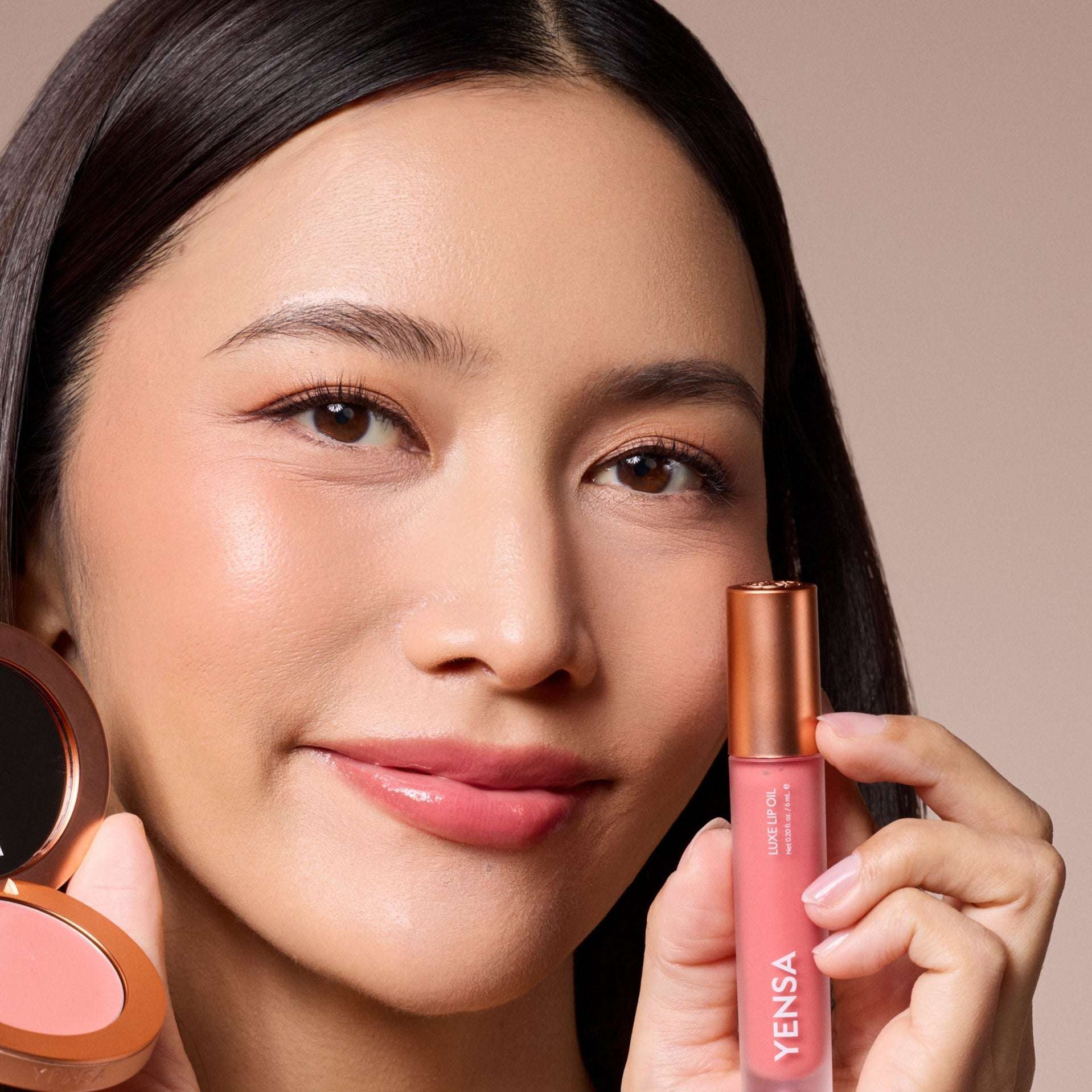 Luxe Lip Nourishing Oil in a pink tube with a copper cap, shown beside glossy rosy-pink lips