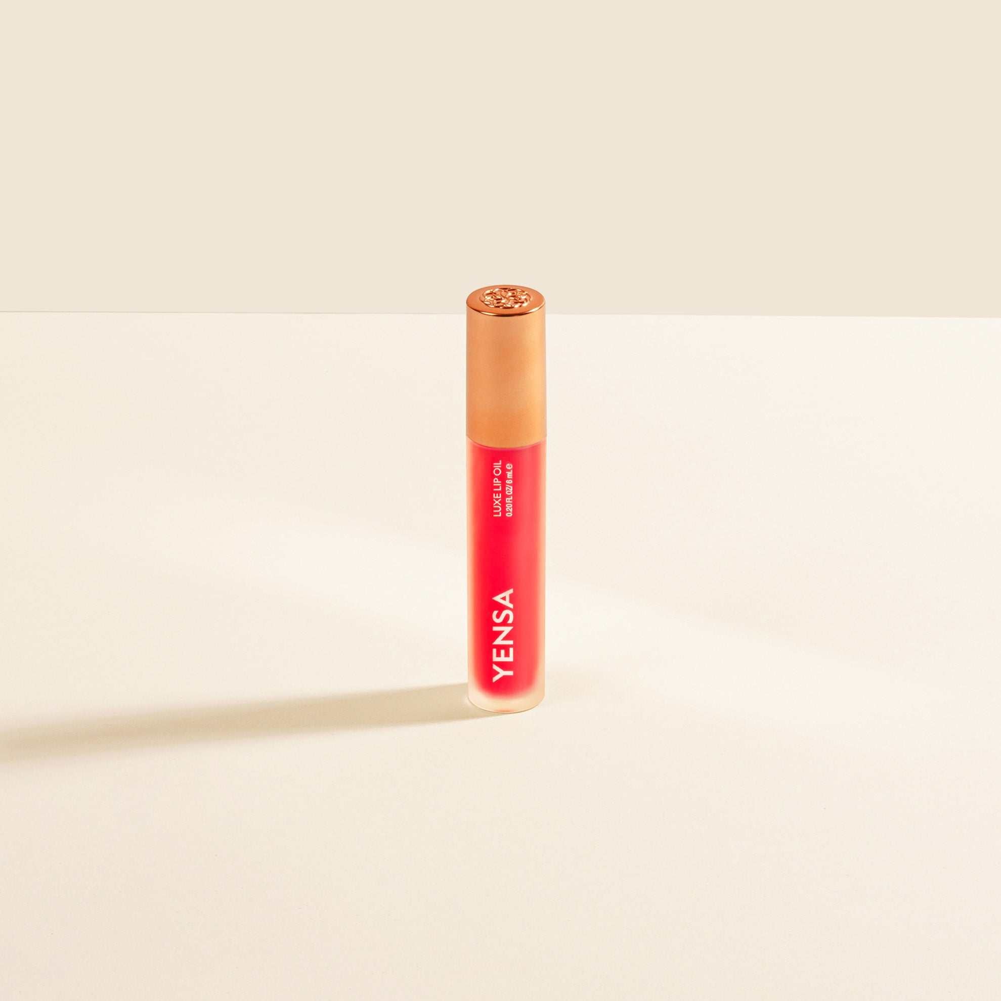 Luxe Lip Nourishing Oil in a slim red and orange translucent tube with a rounded cap and vertical white branding