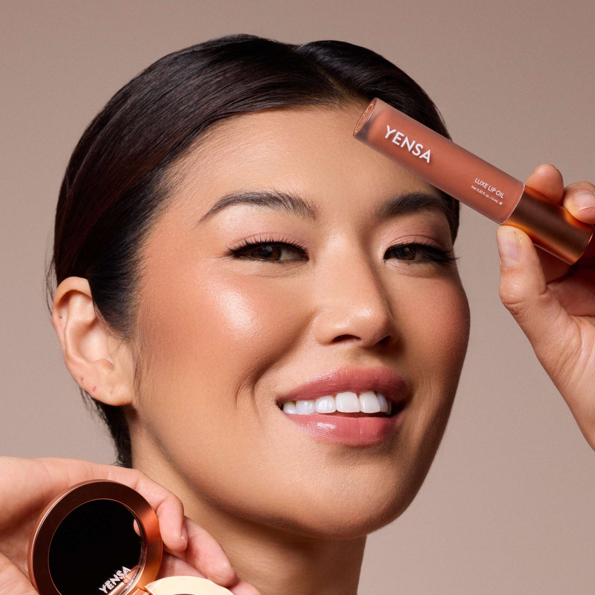 Luxe Lip Nourishing Oil, a warm rosy-brown gloss in a clear tube with a metallic bronze cap, shown on smiling lips