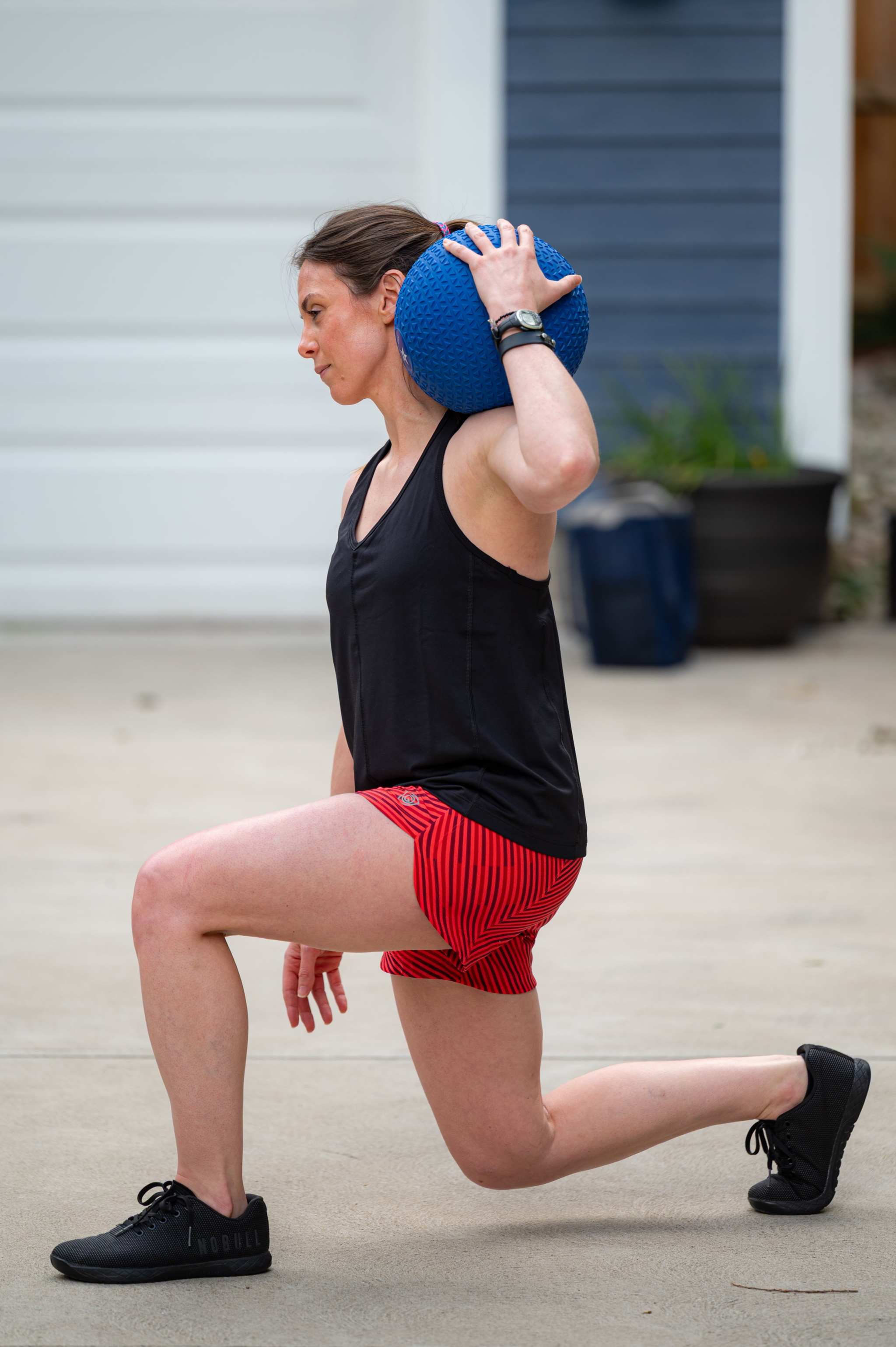 Mesh It To Me Tank in black mesh with a V-neck and sleeveless cut, worn with red striped shorts during a lunge