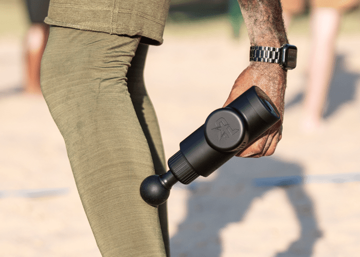MVP+ Percussion Massage System, black handheld percussion massager with rounded attachment applied to leg