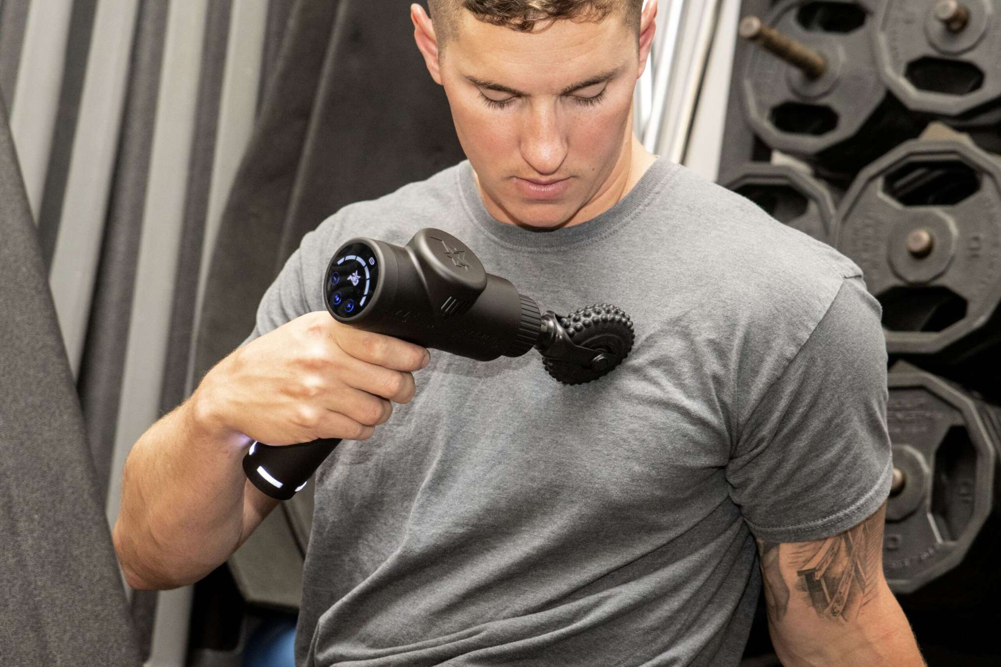 MVP+ Percussion Massage System, black handheld massager with textured dual-head attachment in use