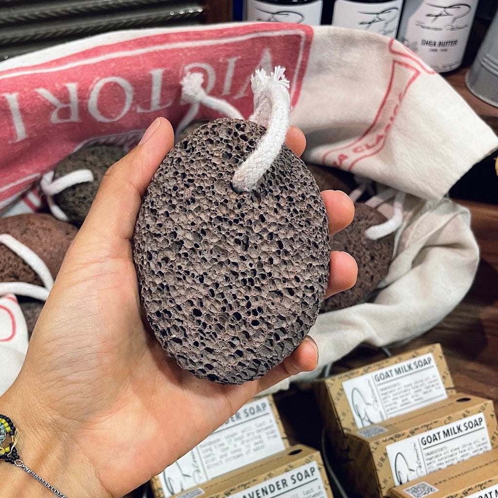Natural Volcanic Lava Stone pumice exfoliator in dark gray porous volcanic rock, oval-shaped with a white hanging cord