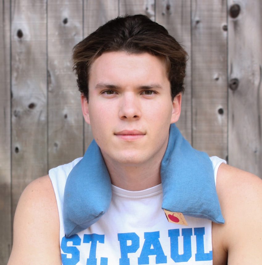 Neck Wrap in Blue Denim draped around the neck, made of soft blue cotton fabric with a stitched, curved shape.