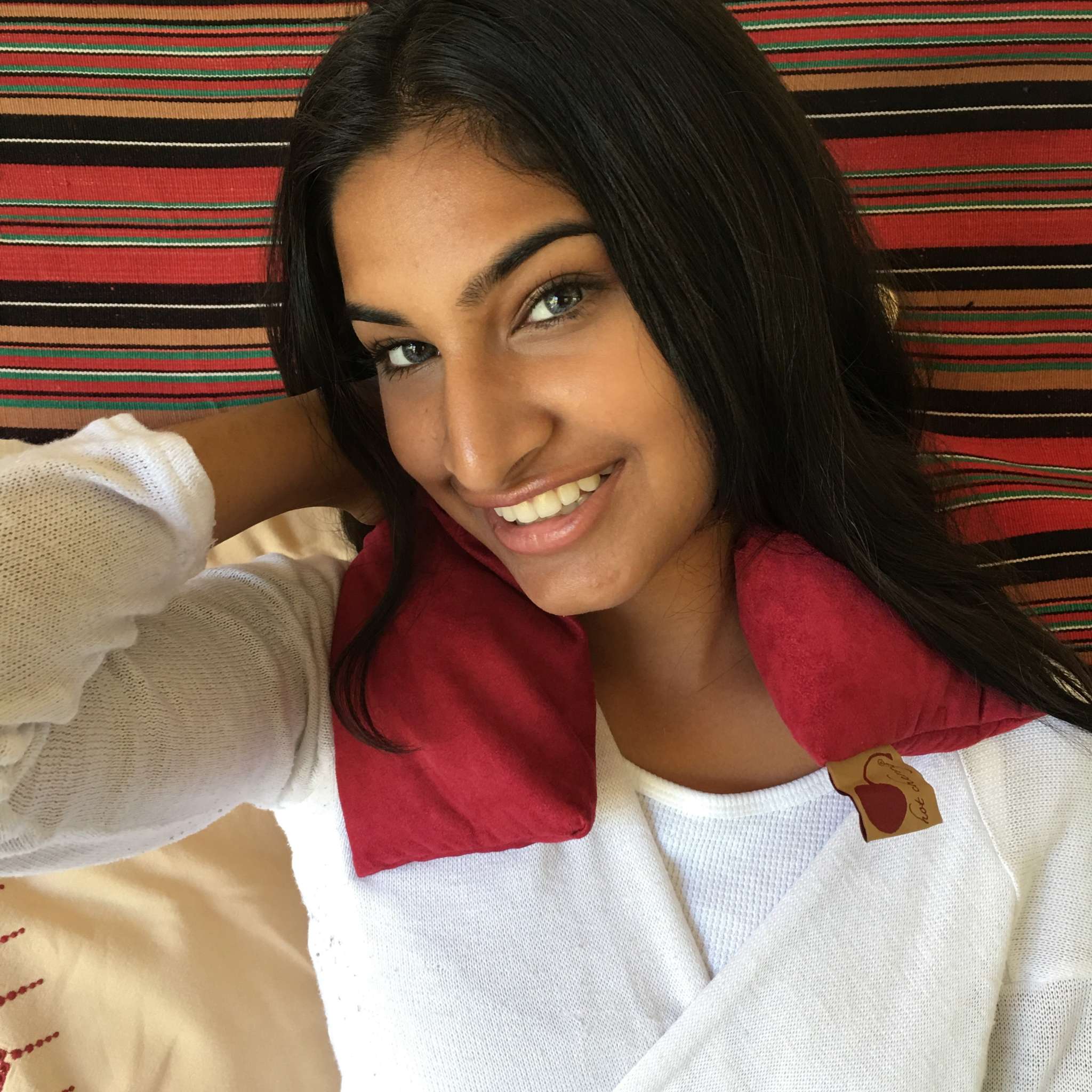 Neck Wrap in deep red plush ultra-suede, draped around the shoulders with a small branded tag