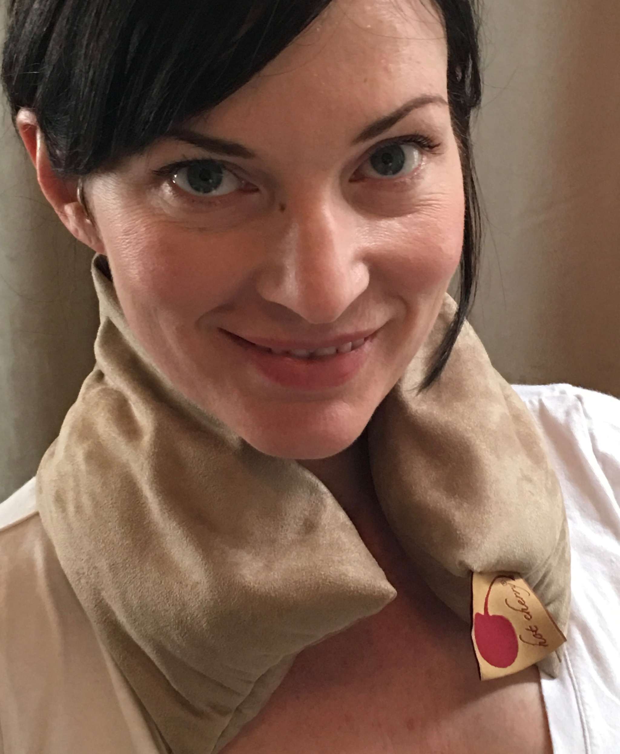Neck Wrap in soft tan plush ultra-suede, draped around the neck with a small attached gift tag.