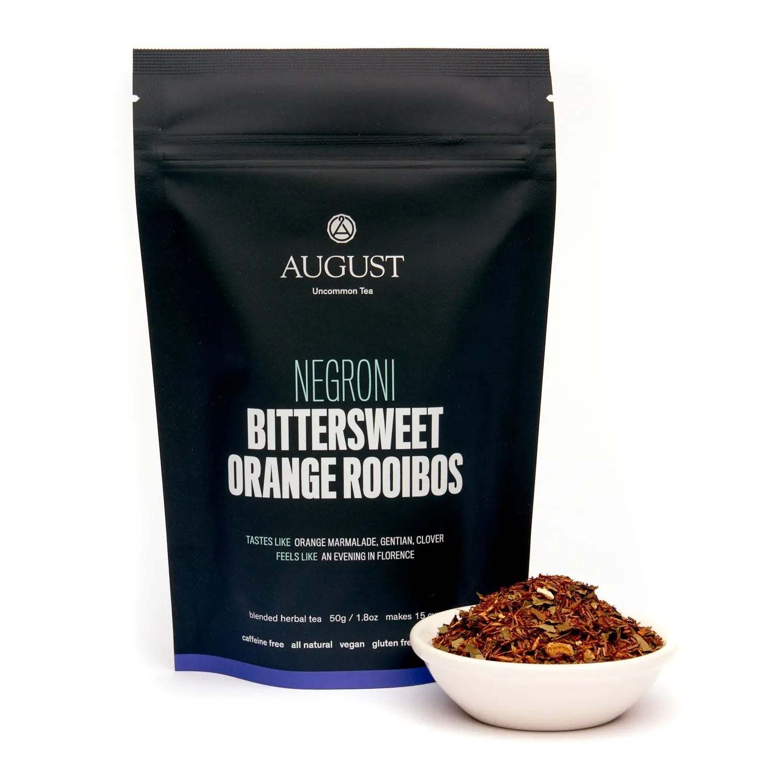 Negroni bittersweet orange rooibos tea in a black resealable pouch, with loose reddish-brown tea in a white bowl.