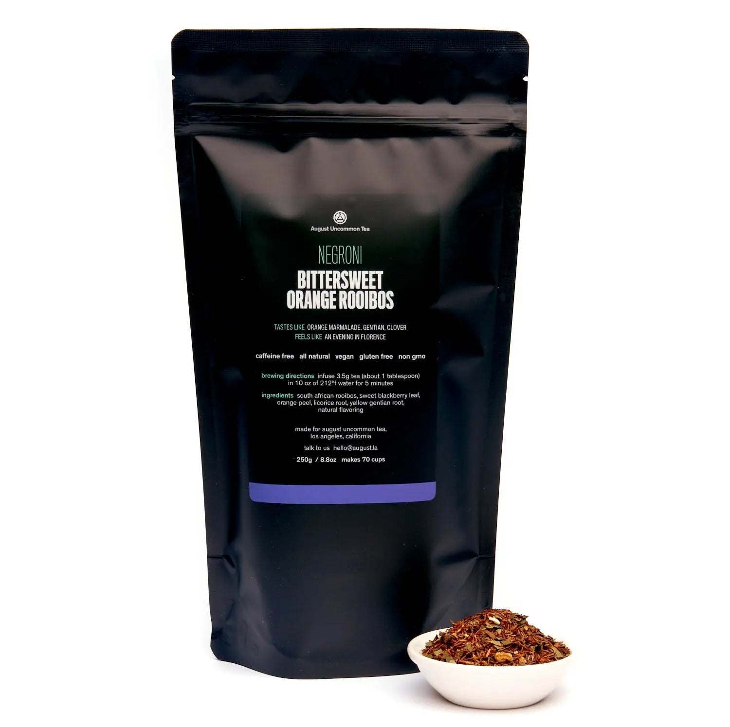 Negroni rooibos tea in a matte black resealable pouch with a bowl of loose reddish-brown tea leaves