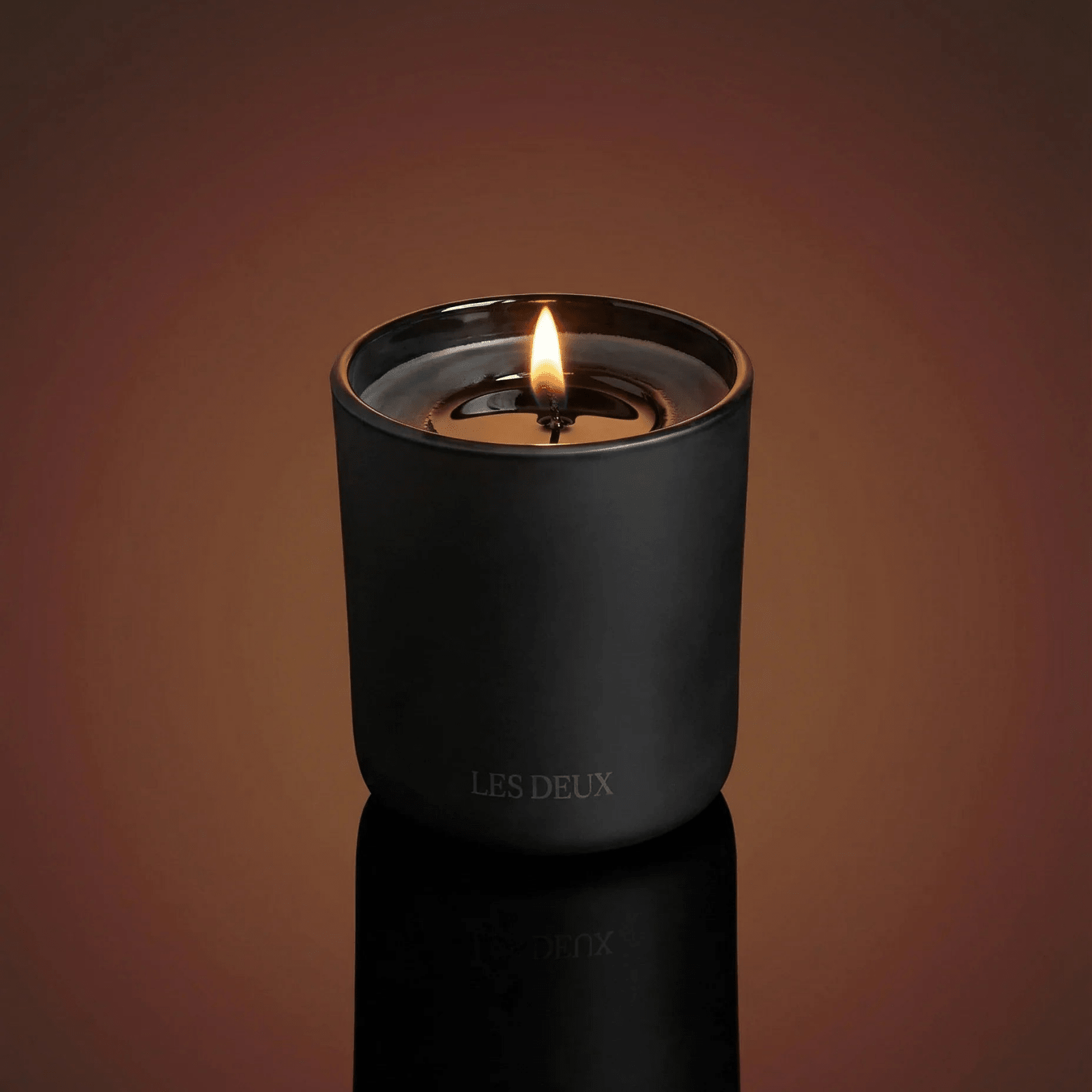 No. 1 - Bois Sacré Candle in a sleek matte black container with natural wax and a glowing flame