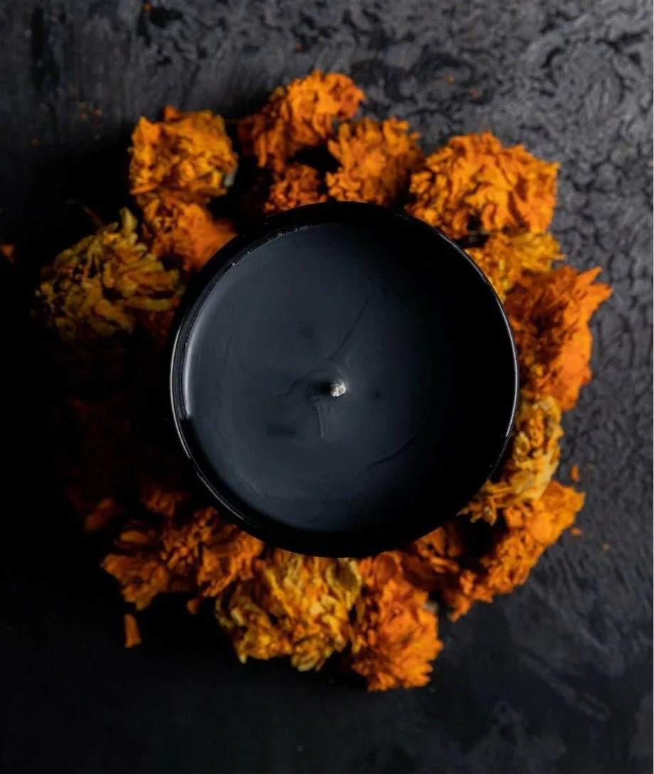 No. 2 - Peau d’Or Candle in a matte black container, surrounded by vibrant orange and yellow marigold flowers