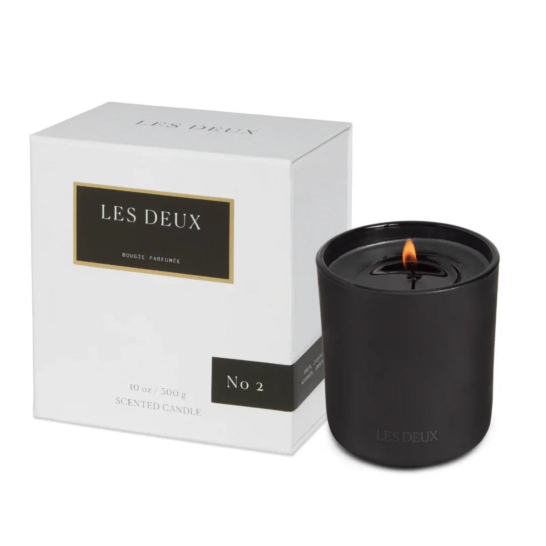No. 2 - Peau d’Or Candle in a matte black vessel with a lit wick beside its white branded box