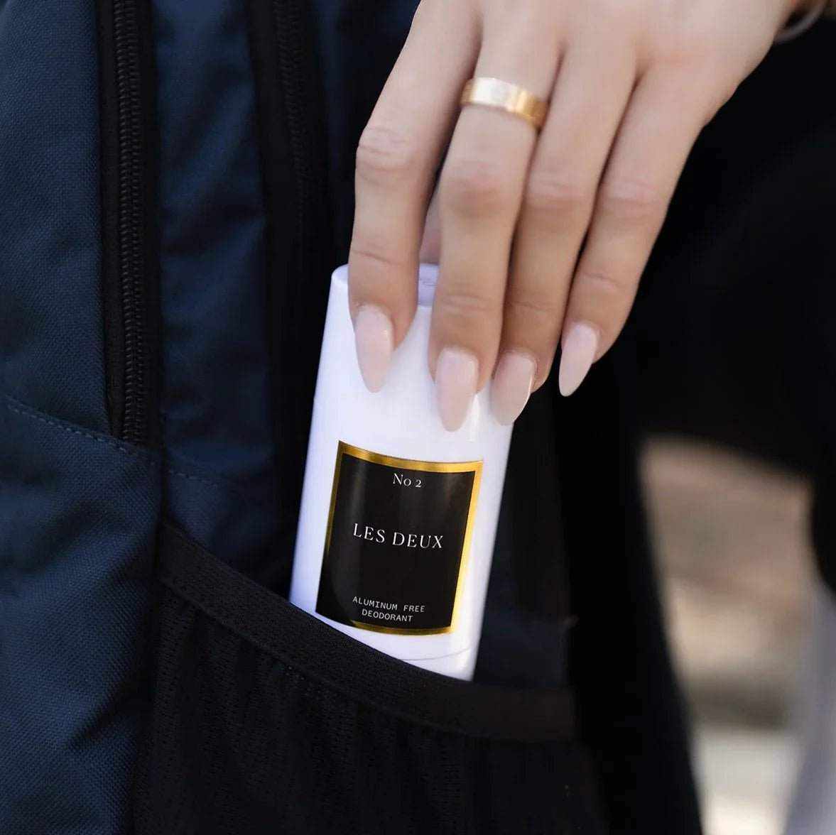 No. 2 - Peau d’Or Deodorant in a white cylindrical case with black and gold label, held by hand