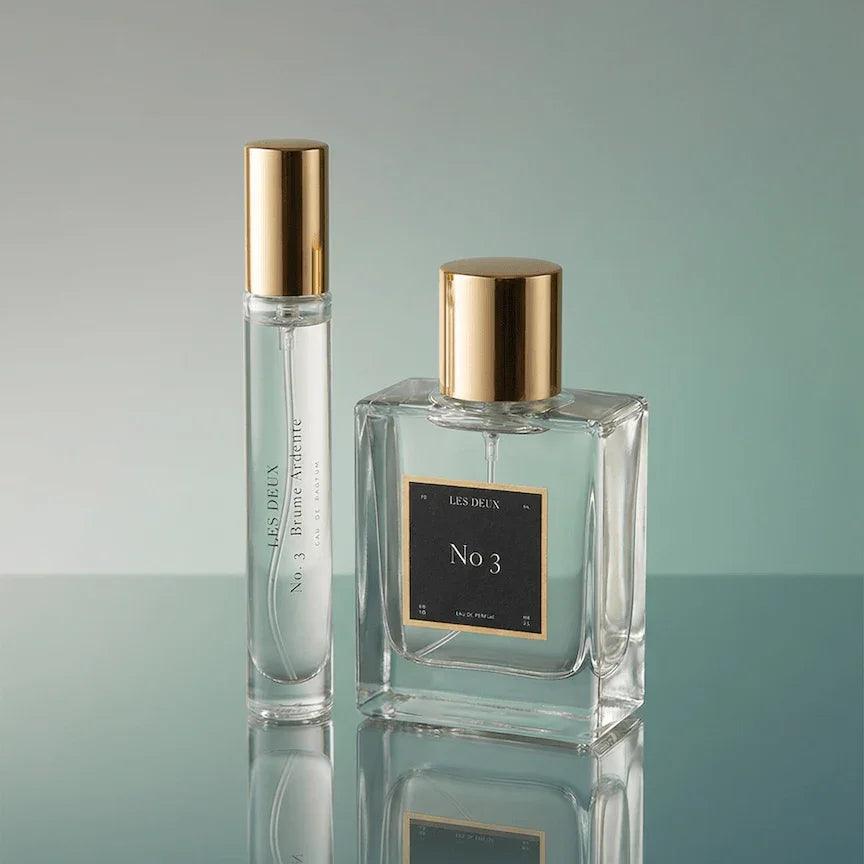 No. 3 - Brume Ardente Perfume in clear glass bottles with reflective gold caps and black labels, including sample vial