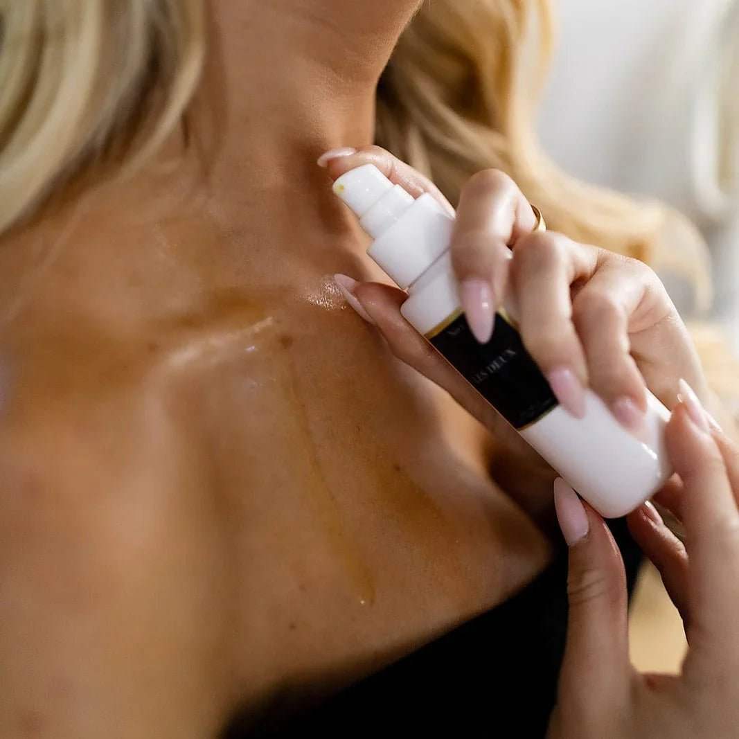 No. 4 - L'Âme Velours Body Oil in a white pump bottle with black label, applied to skin as a fine mist
