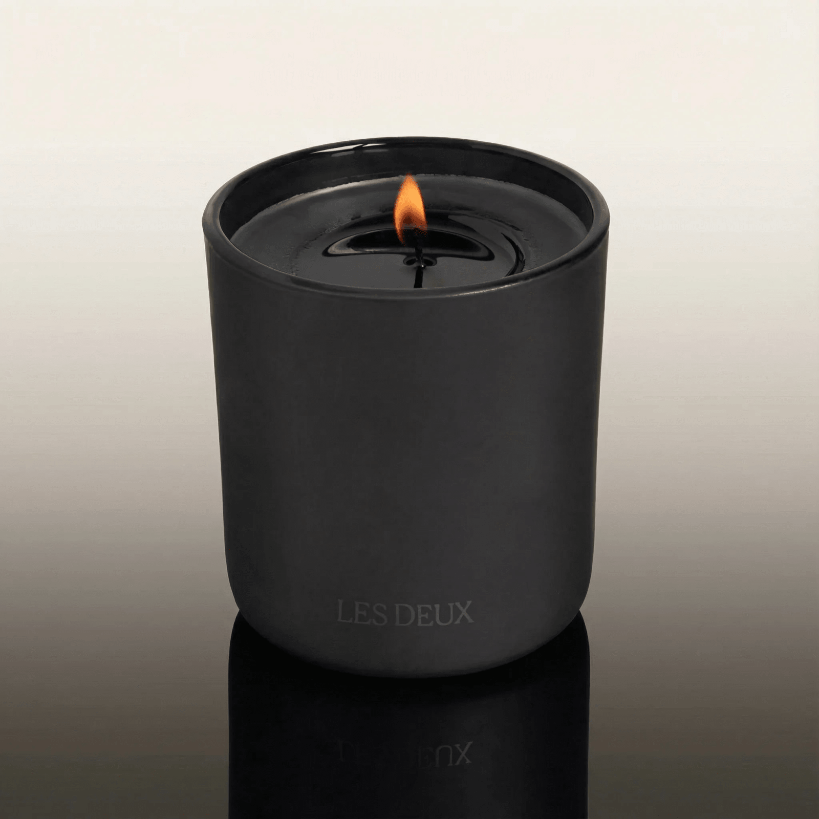 No. 4 - L'Âme Velours Candle in a sleek matte black container with a lit flame and embossed branding