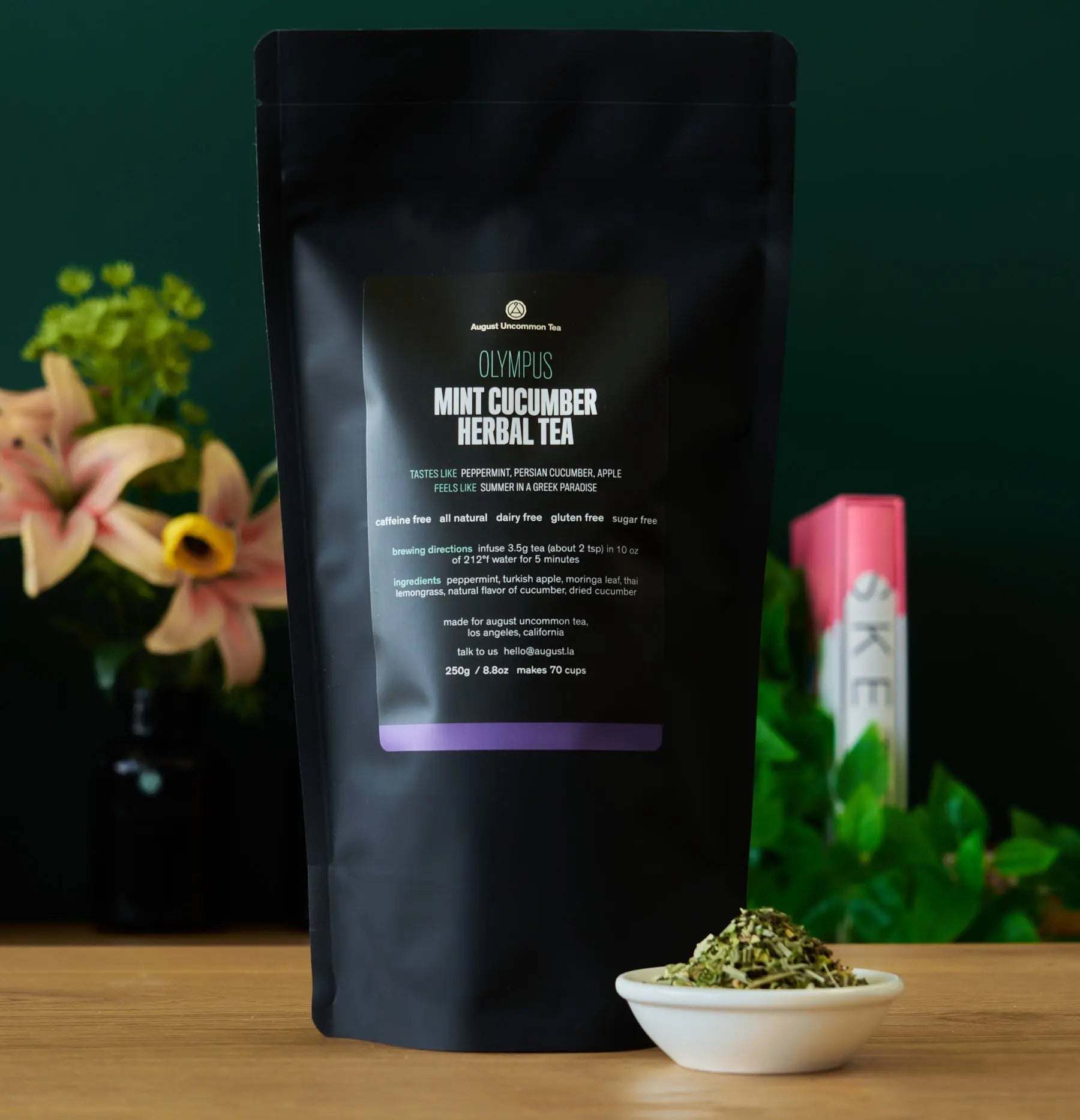 Olympus - Mint Cucumber Herbal Tea in a matte black resealable pouch with purple label and loose herbs beside it