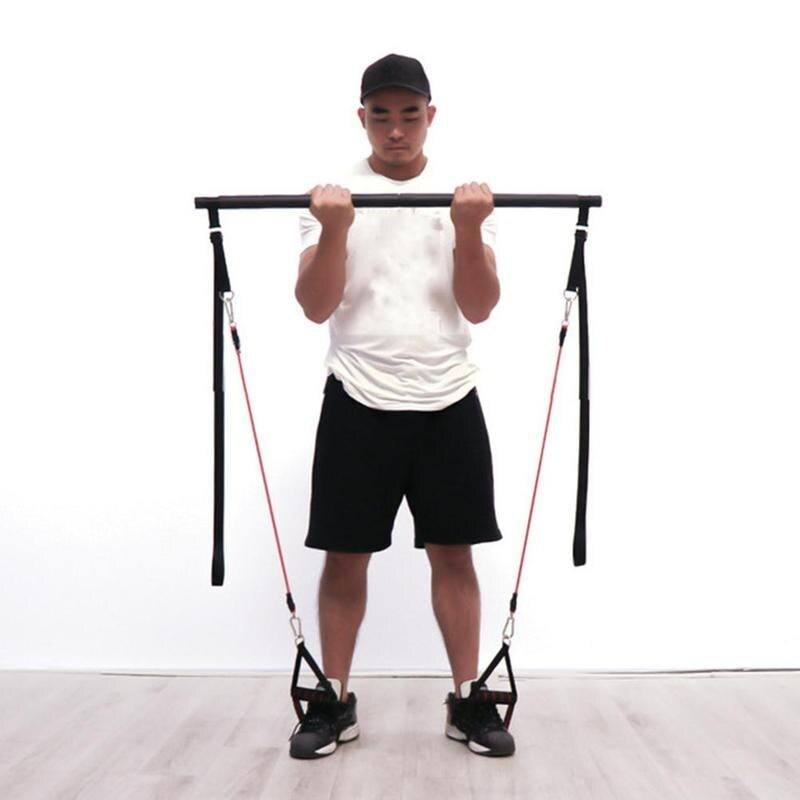 Pilates Bar Kit with black metal bar and red resistance bands featuring foam handles, held by a man in white shirt and black shorts.