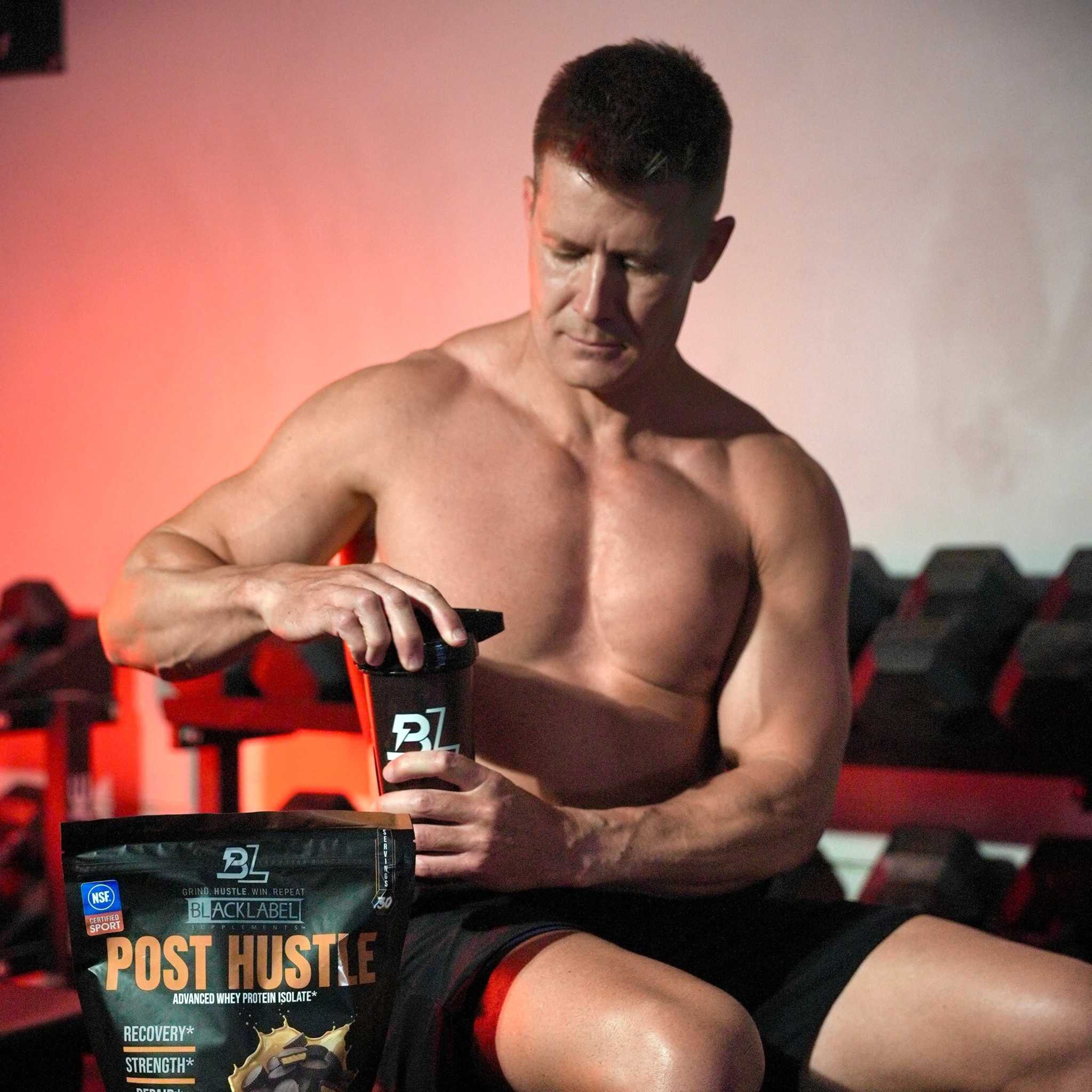 Protein powder pouch in black packaging with bold orange Post Hustle text beside a matching black shaker cup, for post-workout muscle recovery