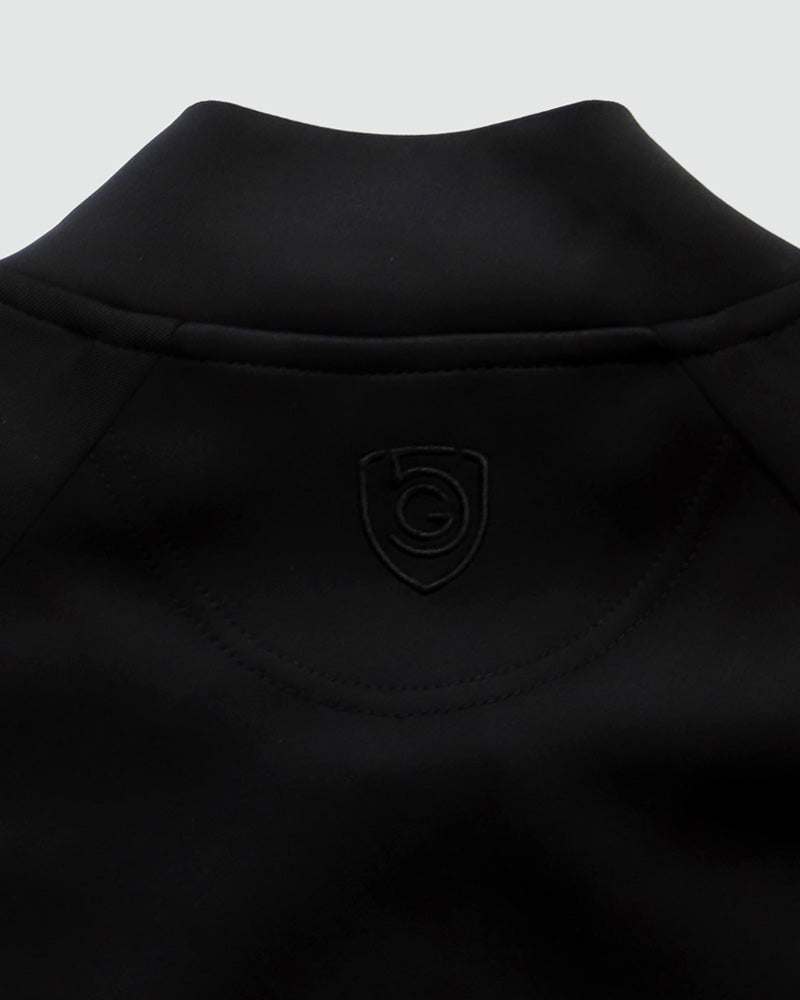 Powerstripe LS Track Jacket in black fabric, showing a raised collar, stitched yoke seams and subtle shield logo