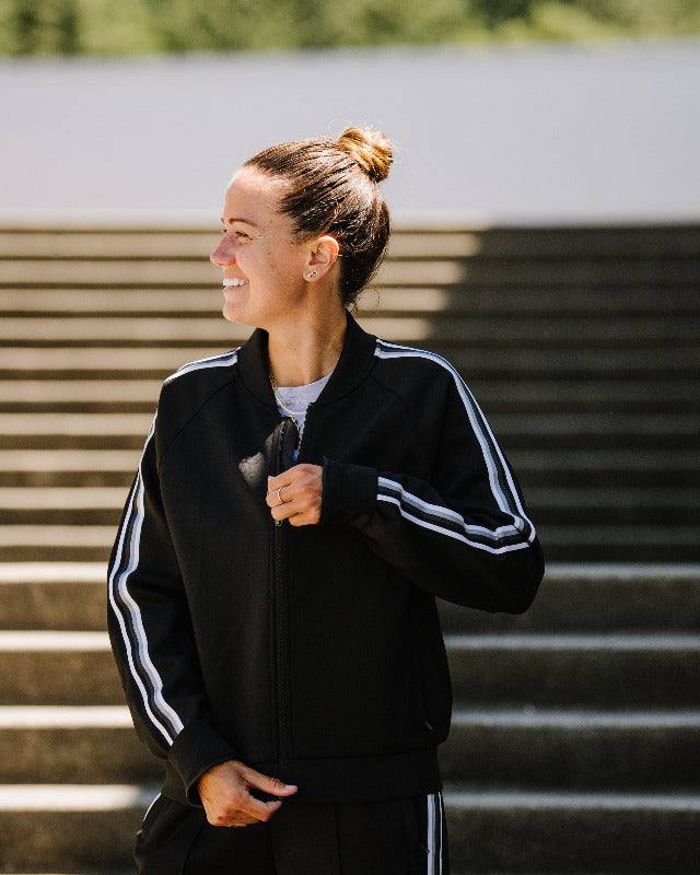 Powerstripe LS Track Jacket in black with white double sleeve stripes, a front zip, stand collar and ribbed hem