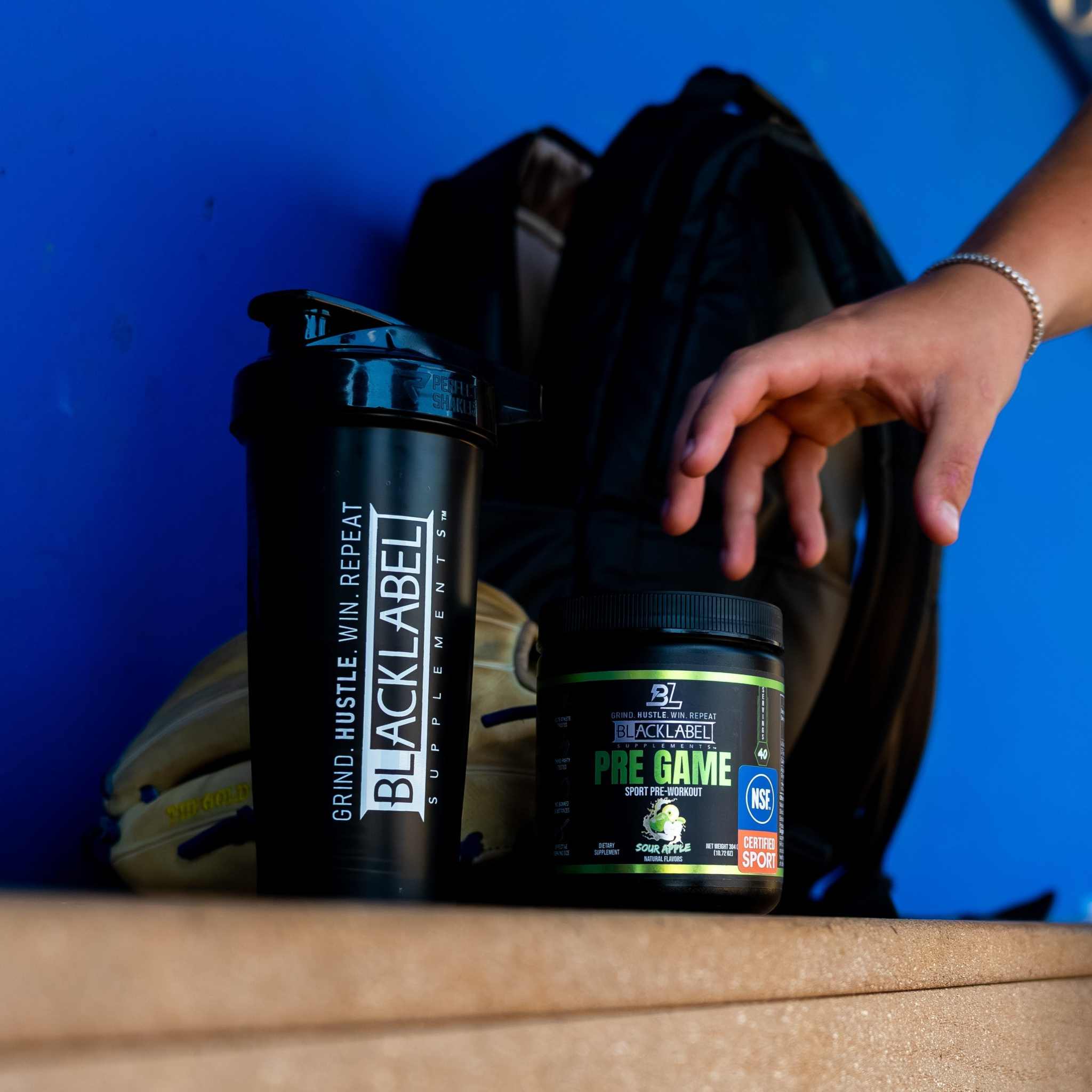 PRE GAME supplement in a black tub with a green label, beside a black shaker bottle and a hand
