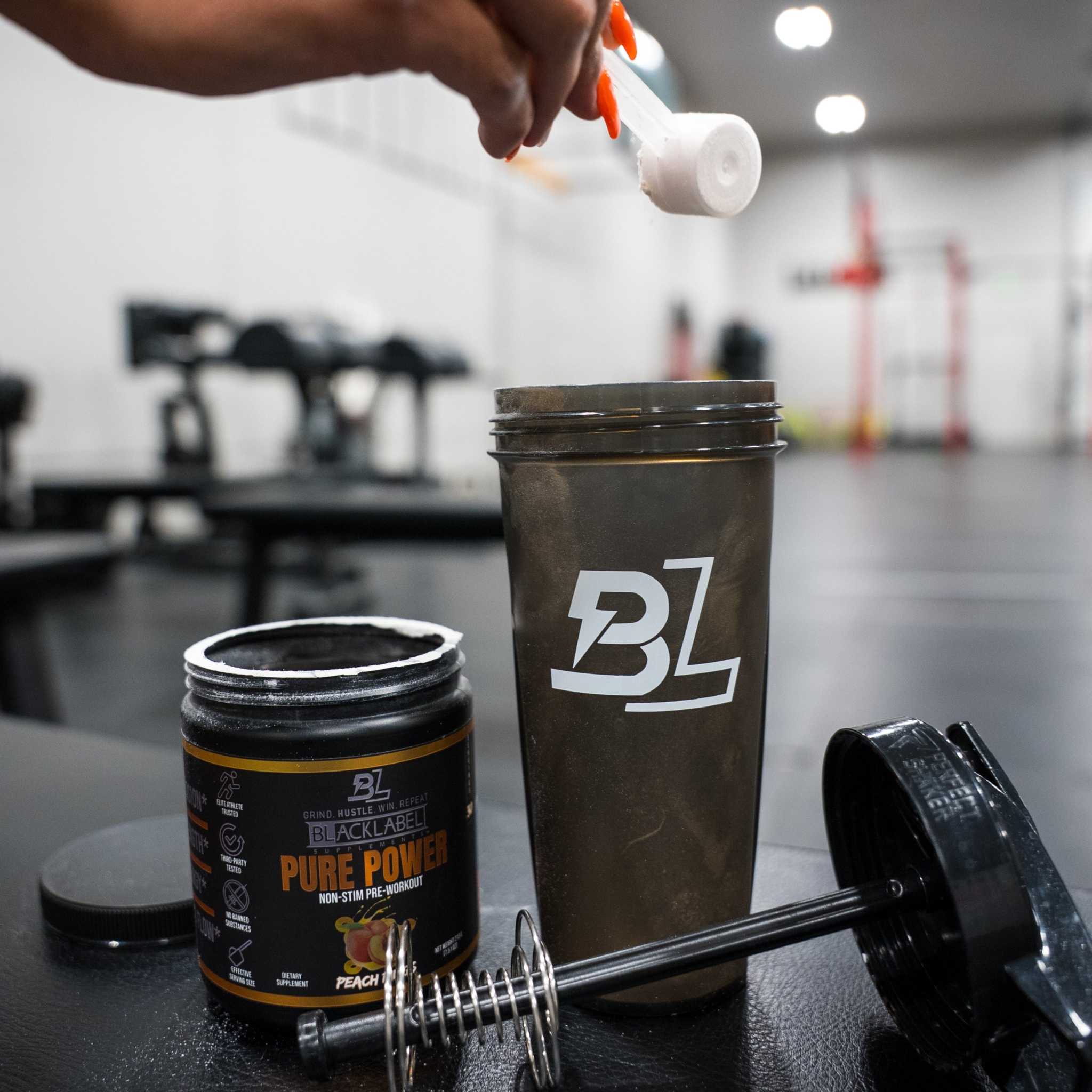 PURE POWER powder supplement in a black tub beside a shaker, with a scoop pouring powder; peach flavor label