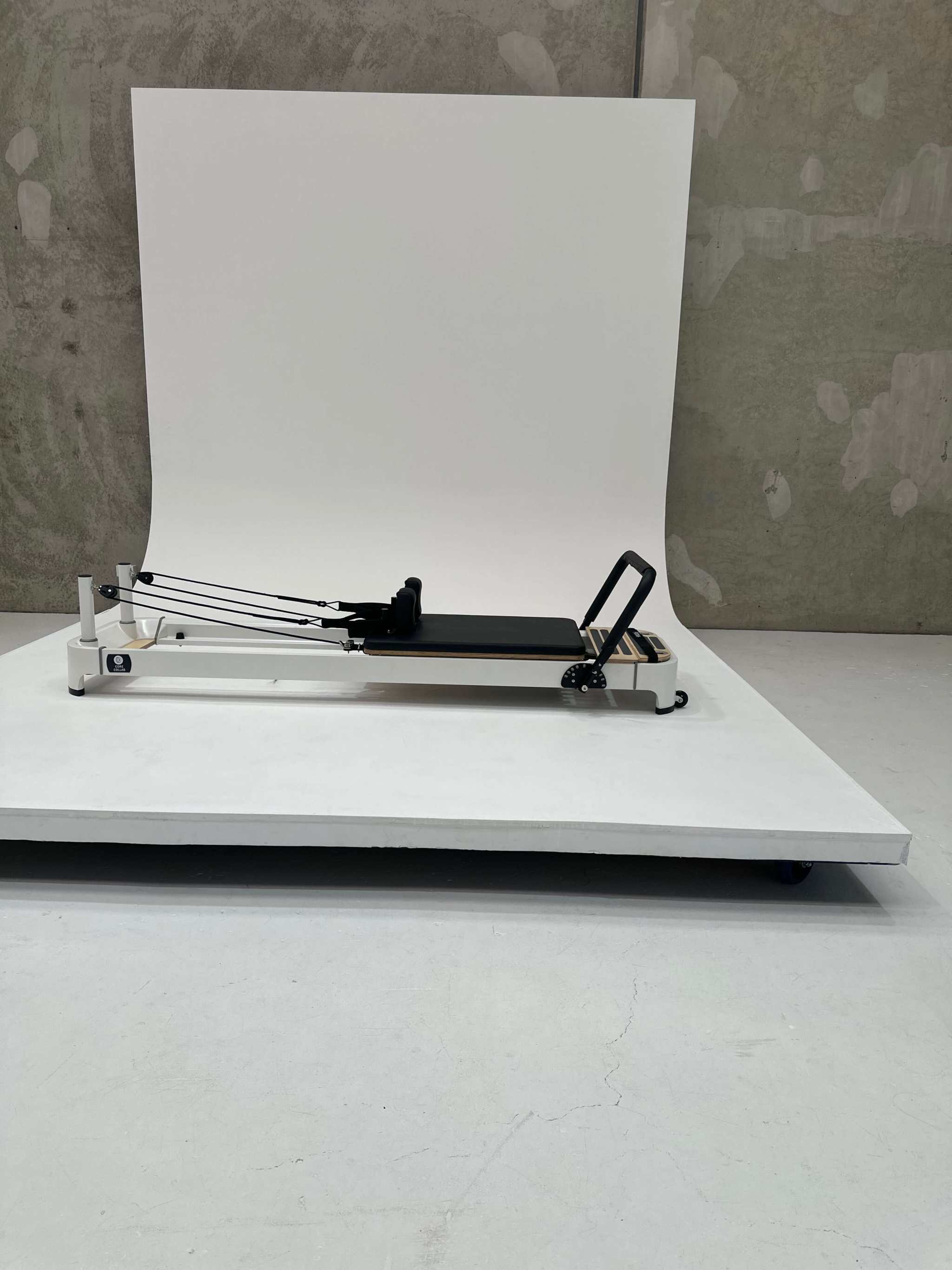 Queen 2.0 Studio Pilates Reformer in beige with black padded carriage, sleek frame, and adjustable footbar