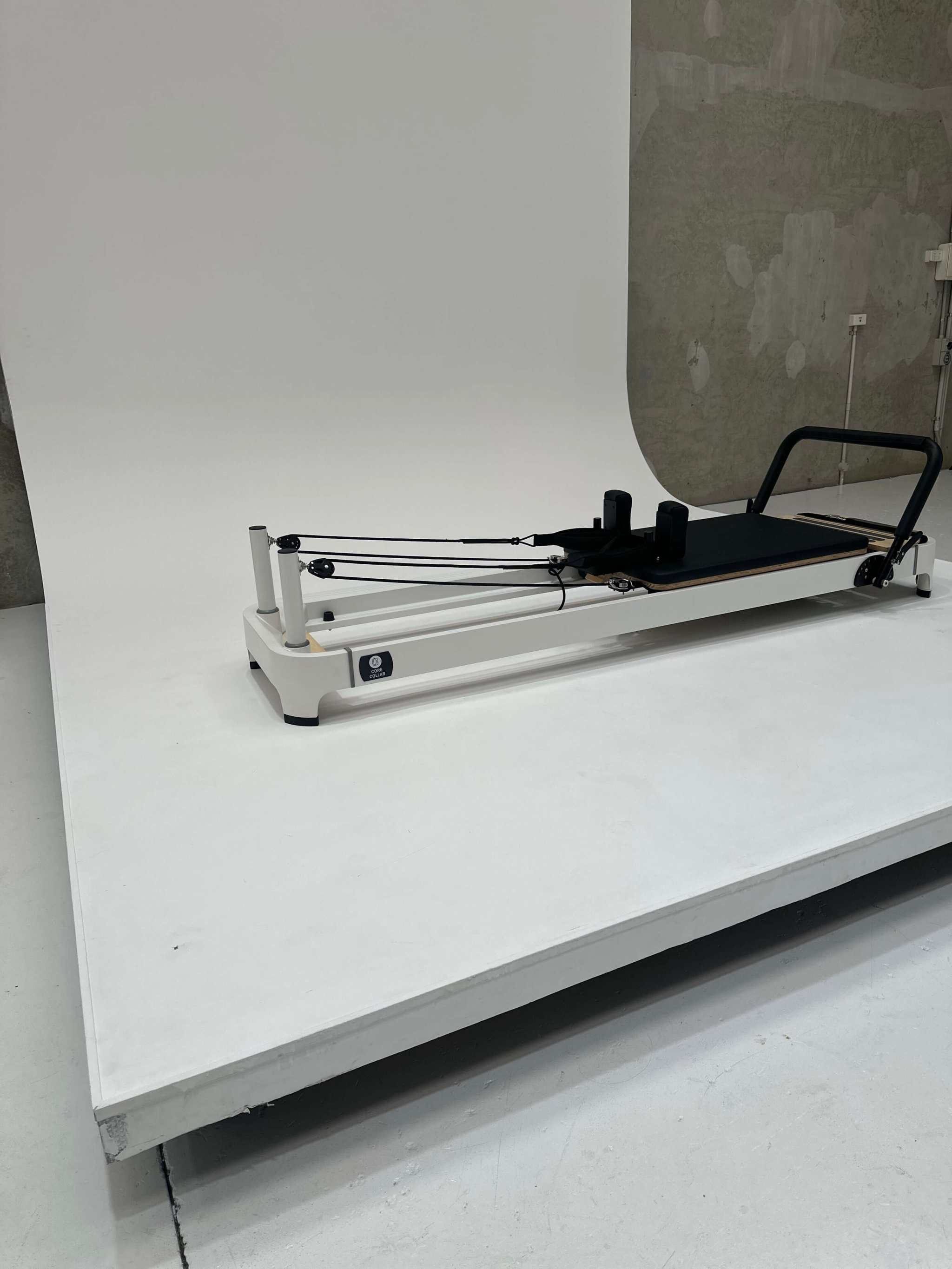 Queen 2.0 Studio Pilates Reformer in beige with sleek frame, black padded carriage, footbar, and precision resistance springs