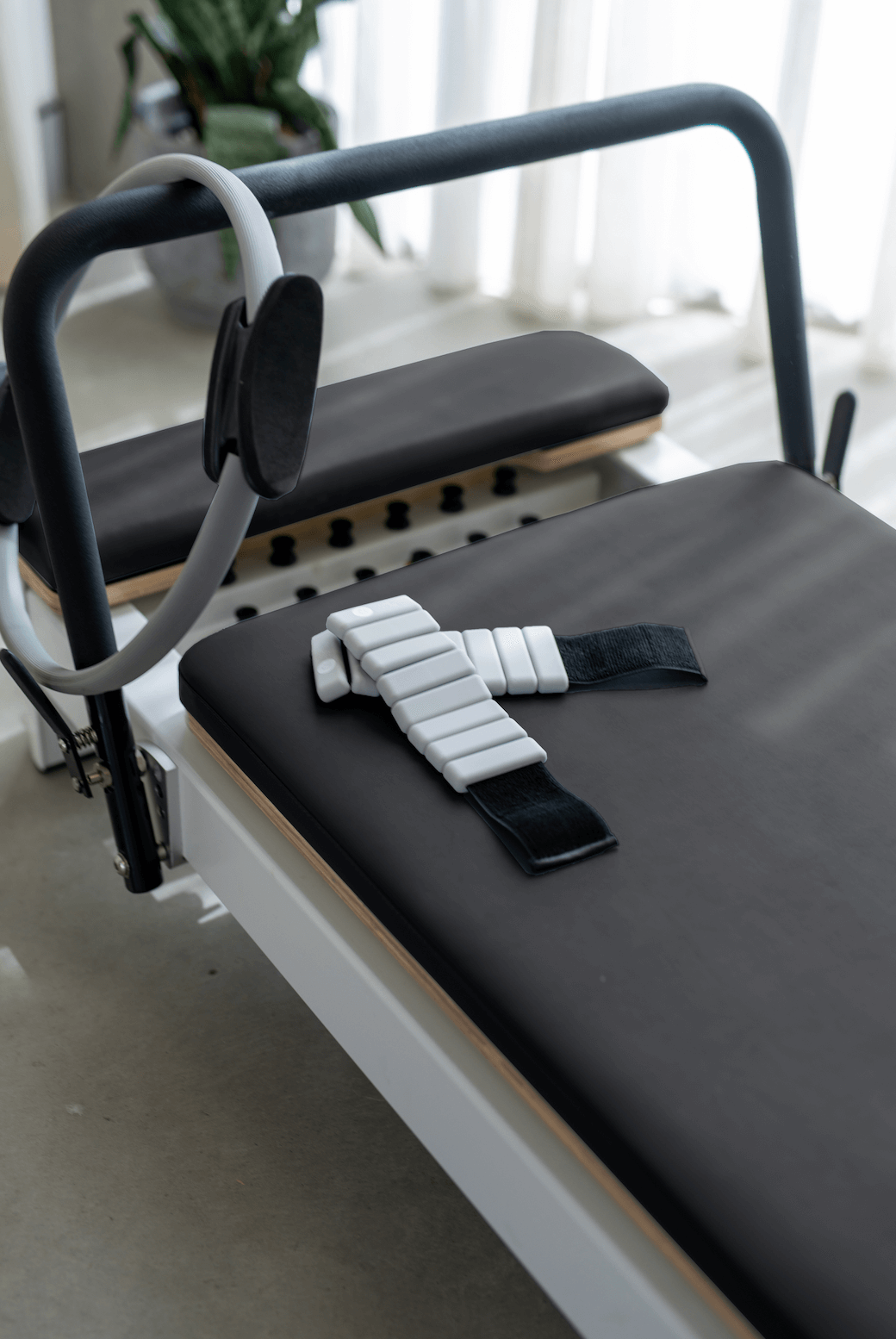Queen Folding Reformer with black cushioned upholstery, gray frame, and adjustable padded headrest for Pilates workouts at home