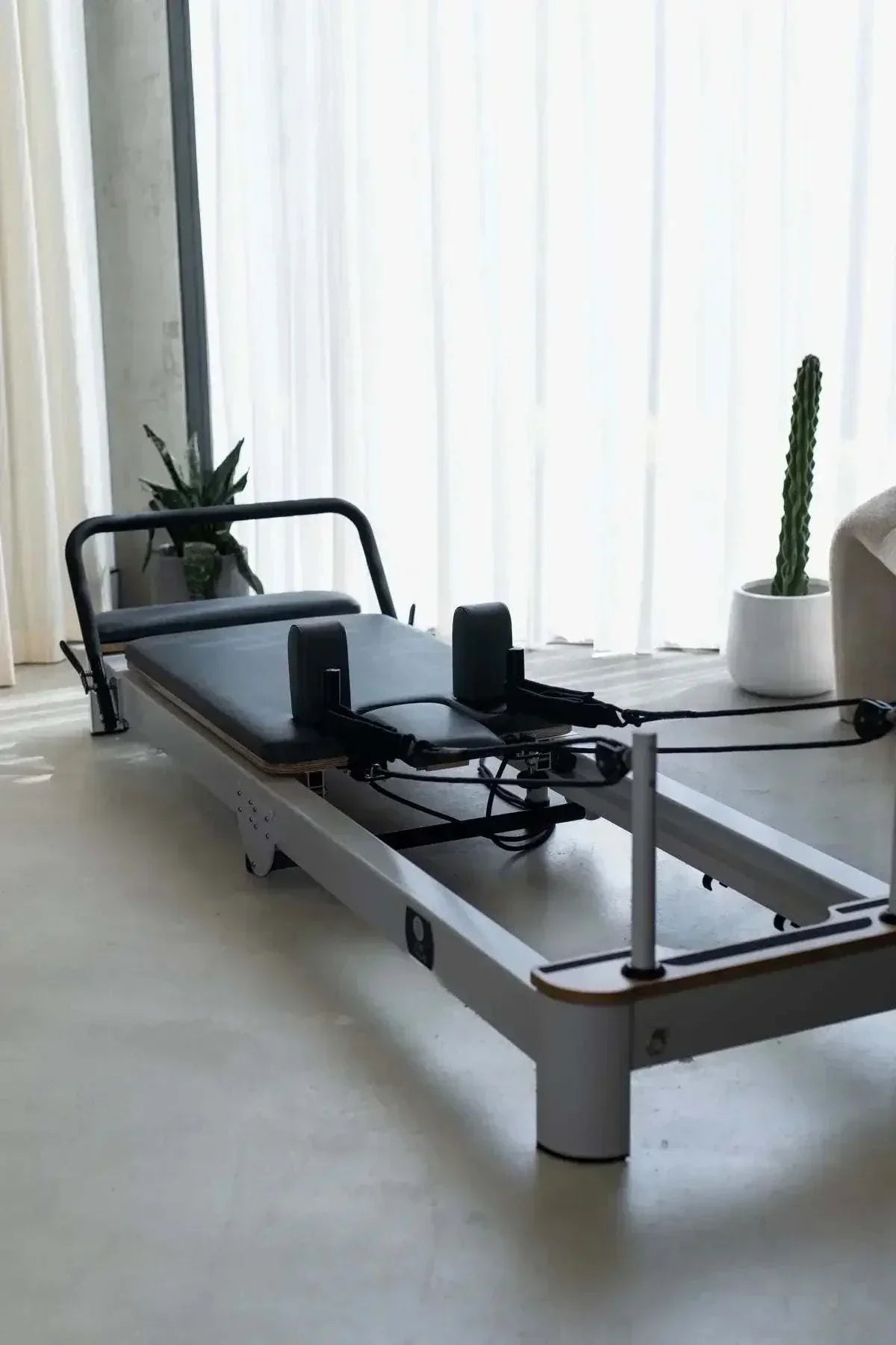 Queen Folding Reformer with white frame, black padded upholstery, adjustable ropes, and a folding design for compact storage