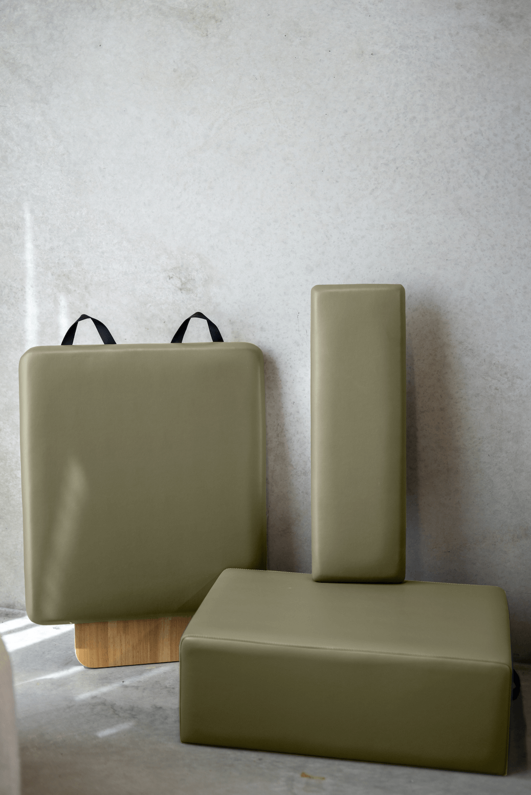 Queen Folding Reformer cushioned accessories in olive green upholstery with smooth, matte finish and black straps for carrying.