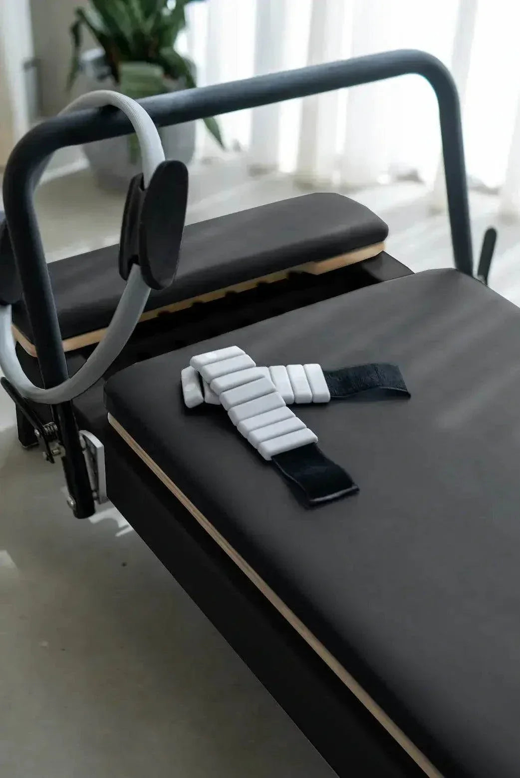 Queen Studio Pilates Reformer with a black padded carriage, gray footbar, and attached Pilates ring for resistance training.