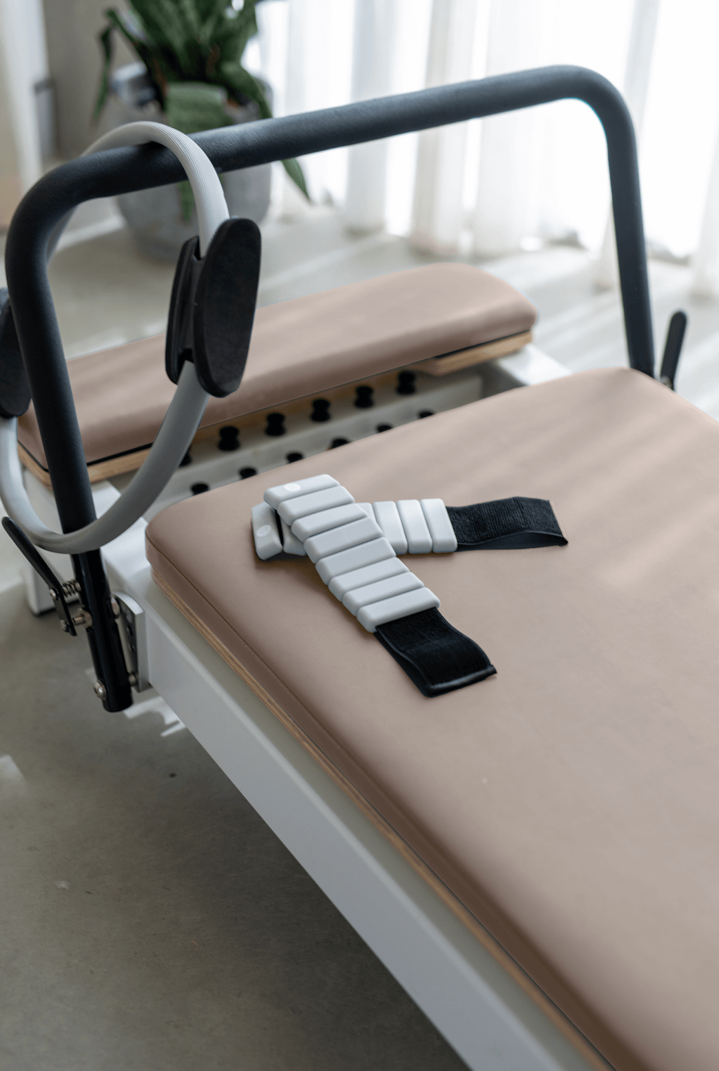 Queen Studio Reformer with beige padded carriage, black frame, and ergonomic foam shoulder rests for Pilates workouts