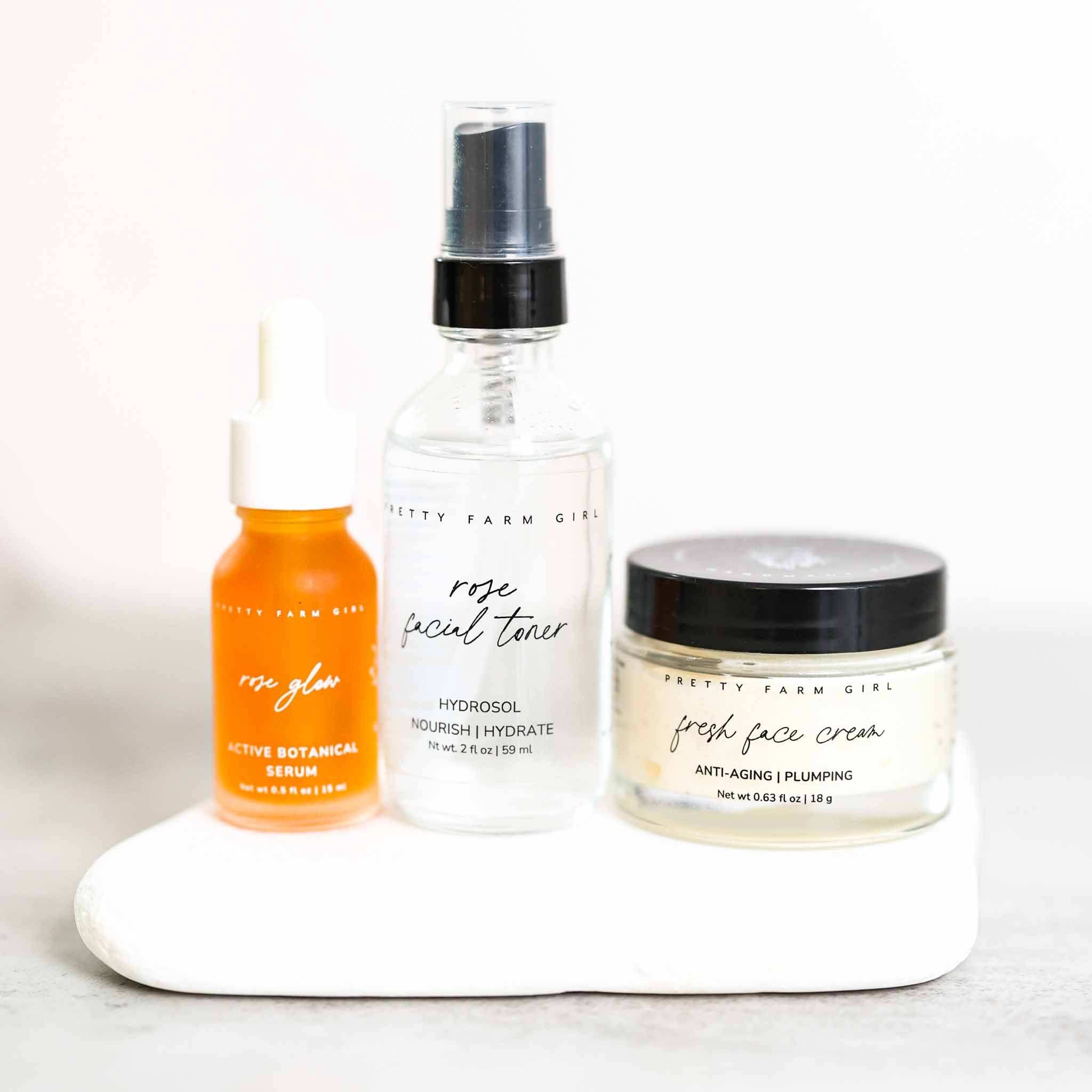 Radiance Glow Kit with orange dropper serum, clear rose facial toner spray bottle, and cream glass jar