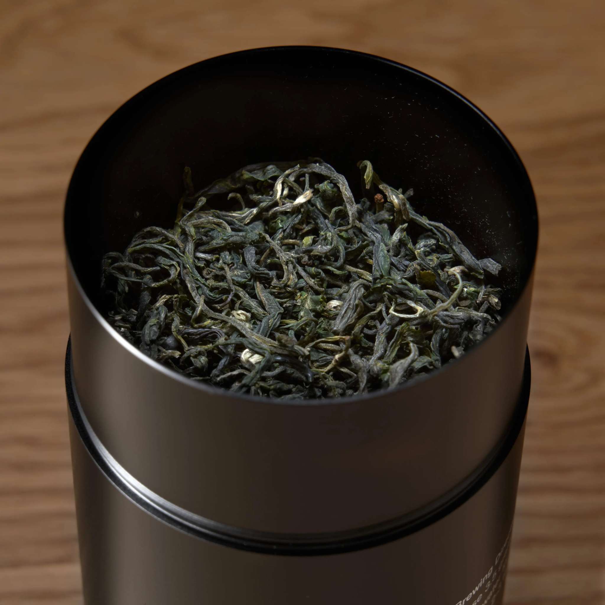 Rare Leaves Emerald - Pi Lo Chun Green Tea in a black metal tin, featuring loose curly green tea leaves