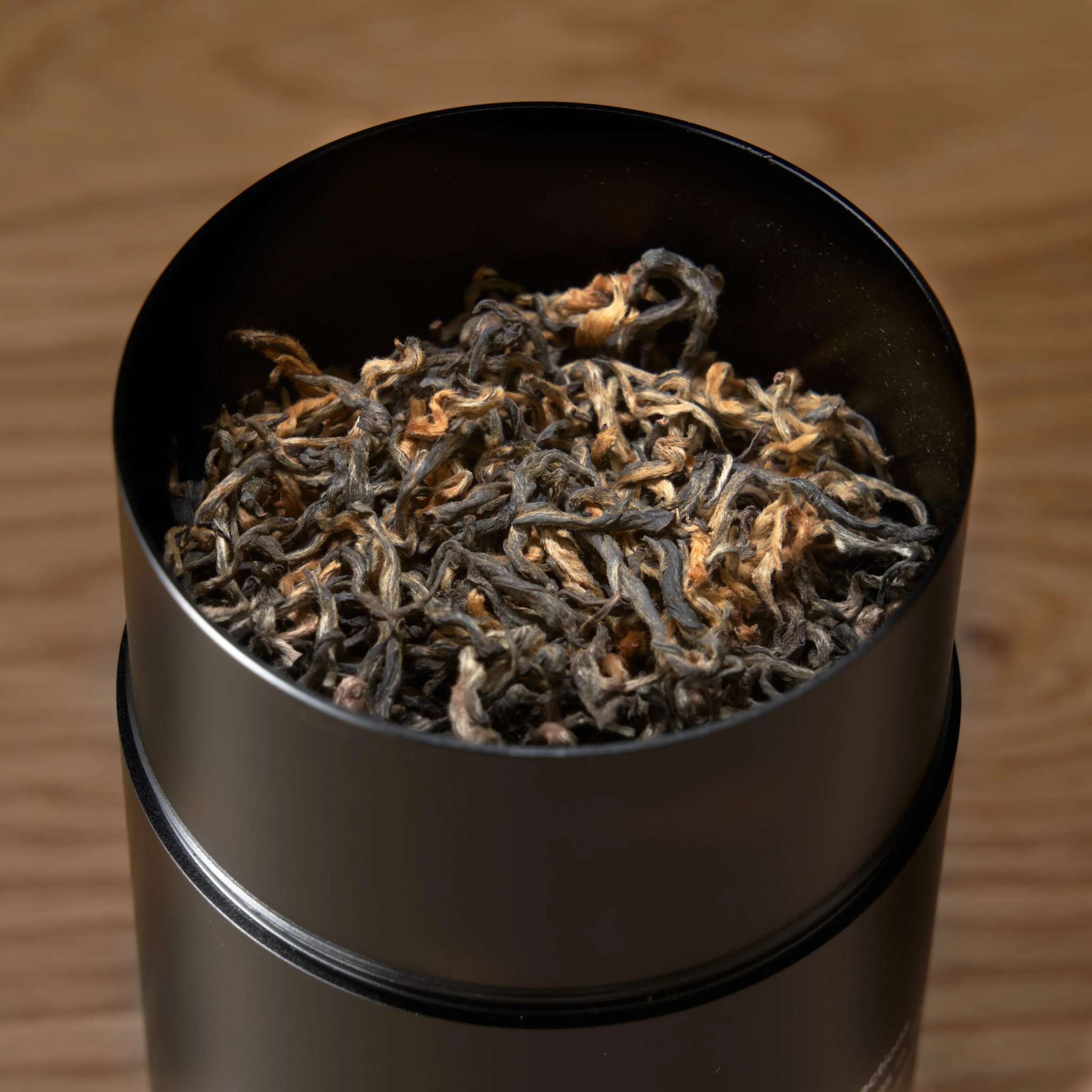 Rare Leaves - Nepalese Black Tea in a black metal tin, filled with twisted dark leaves and golden tips