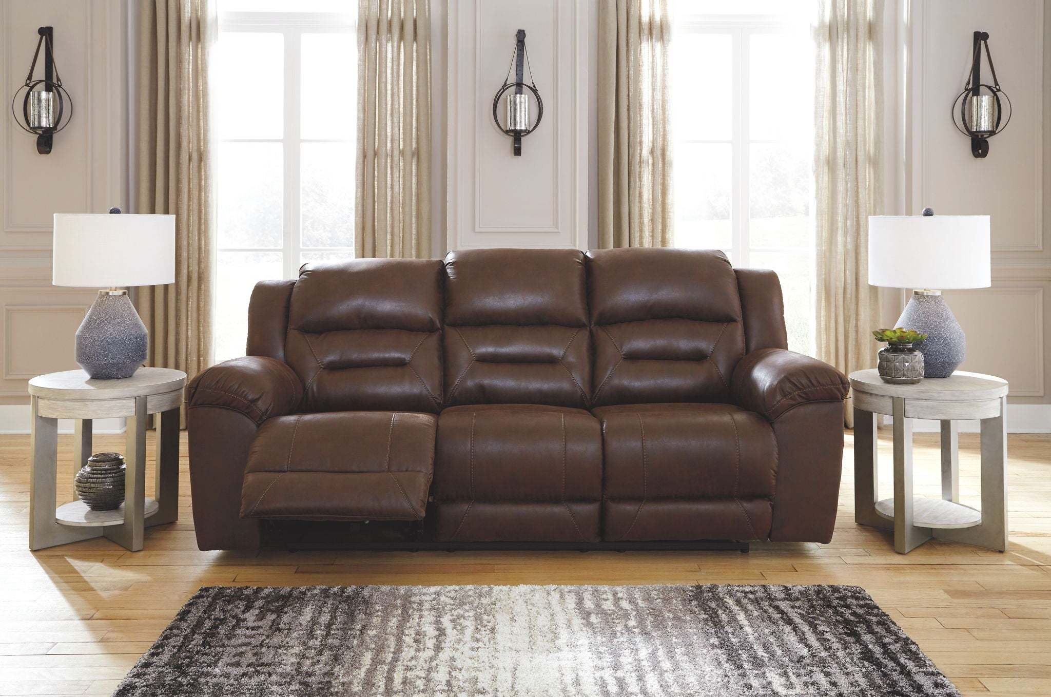 Reclining Living Room Set featuring a brown leather three-seat sofa with padded cushions and one seat reclined for comfort