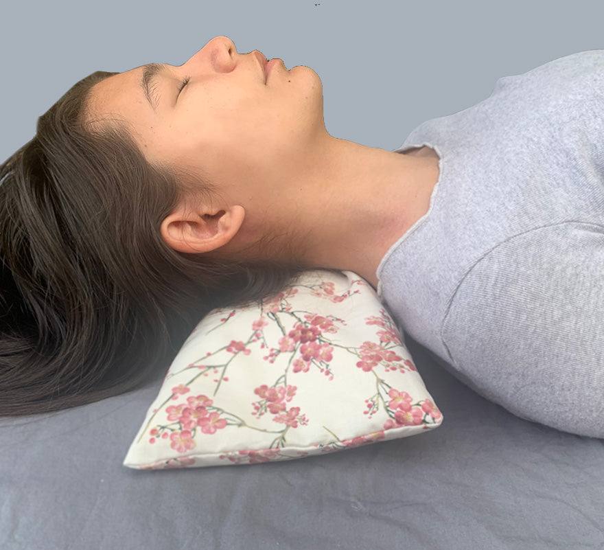 Rectangle/Cervical Pillow with a cherry blossom floral cotton case, shown supporting the neck with a wedge-shaped profile.