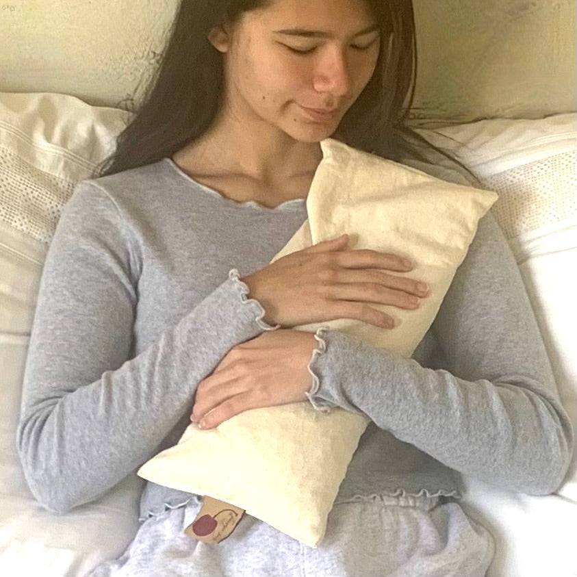Rectangle/Cervical Pillow in natural unbleached fabric, a long rectangular pillow with a subtle cherry print held against the body