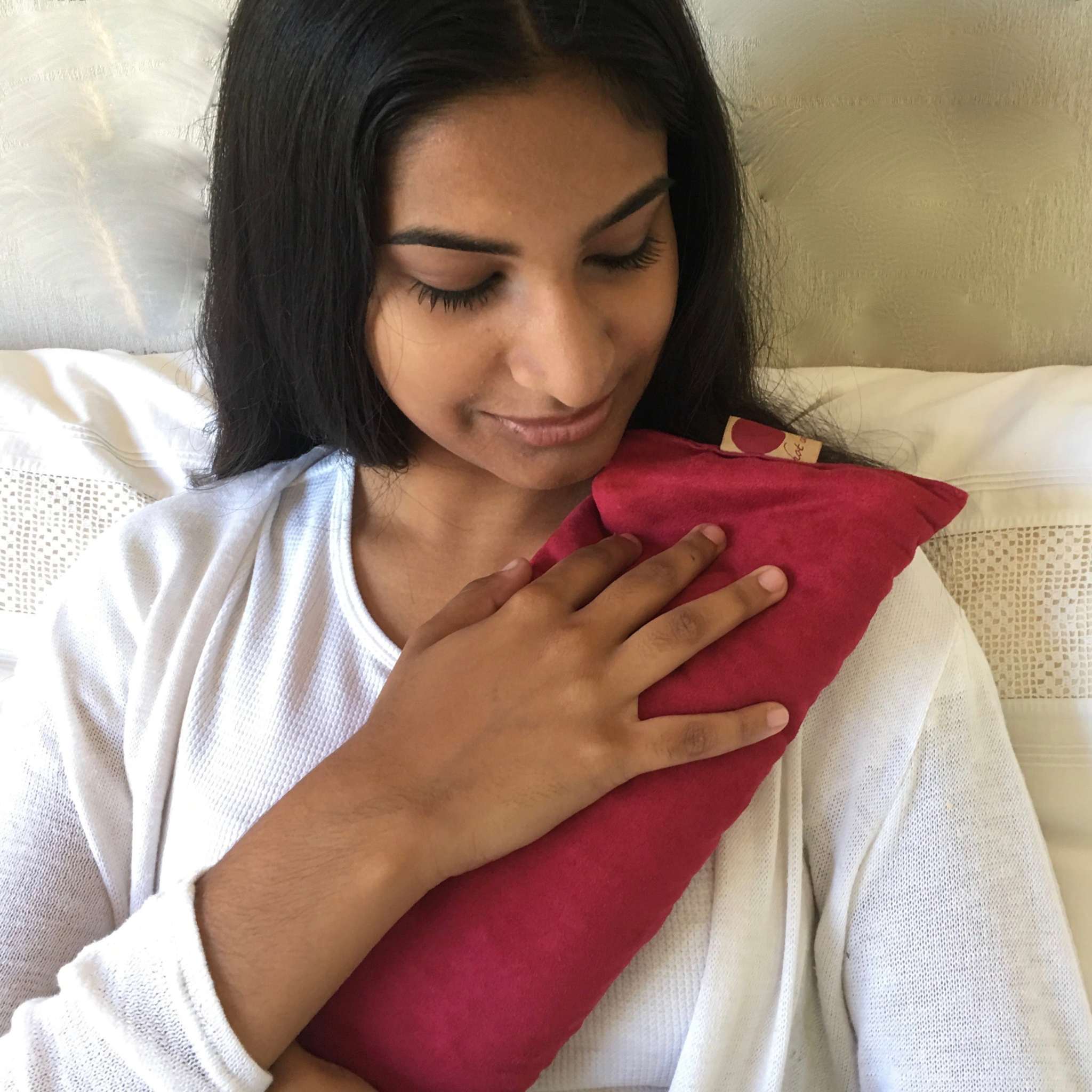 Rectangle/Cervical Pillow in deep red fabric, with a soft rectangular shape held against the chest