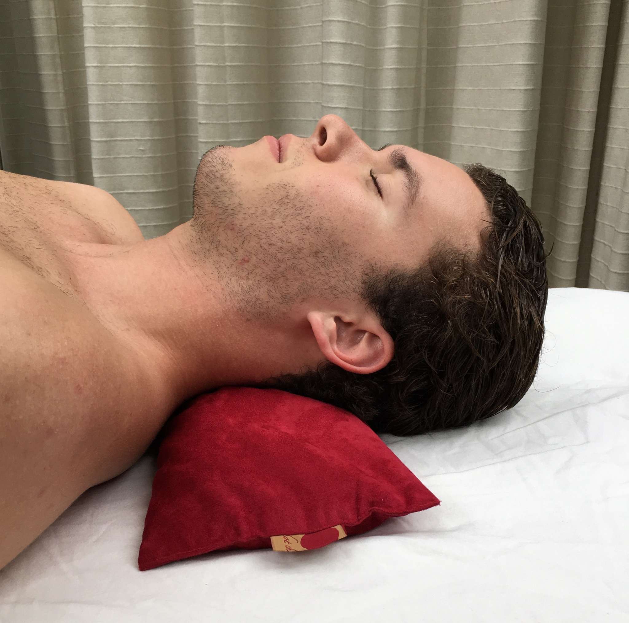 Rectangle/Cervical Pillow in red ultra-suede, supporting a person's neck with its compact rectangular shape.