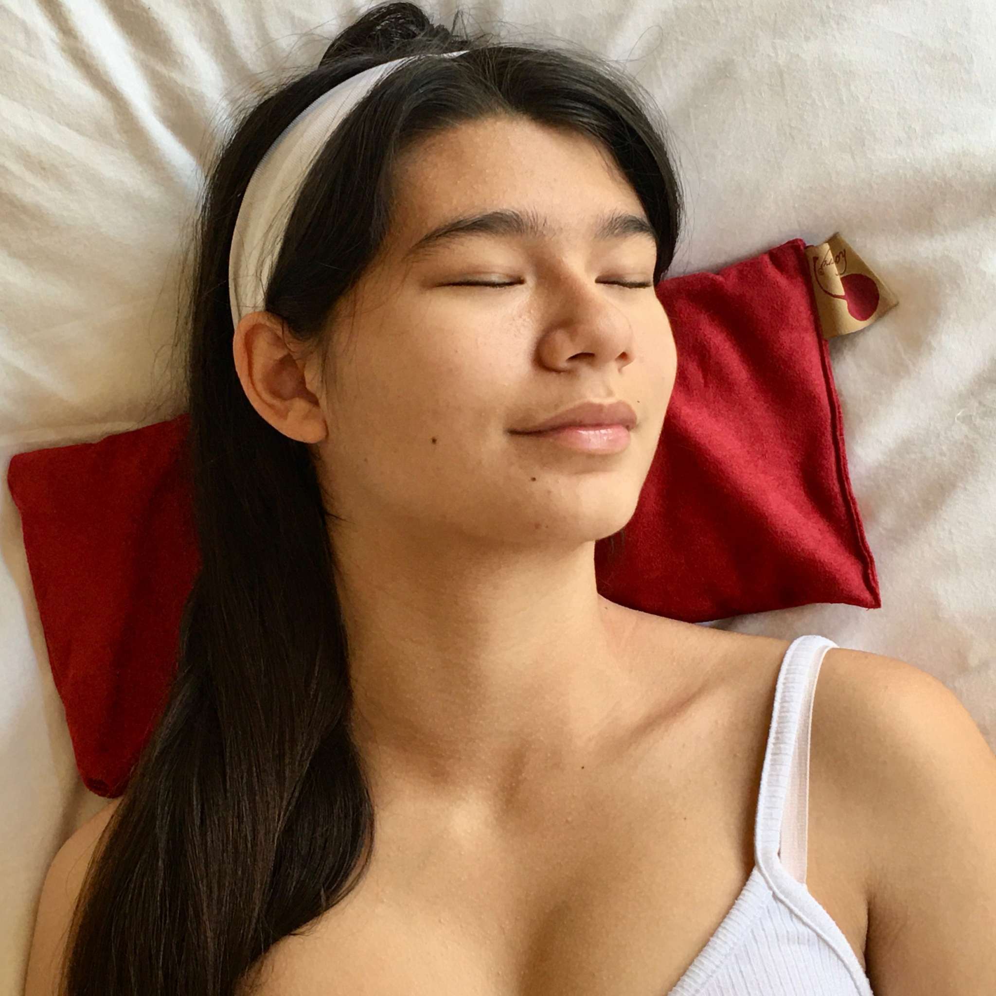 Rectangle/Cervical Pillow in red ultra-suede, a soft rectangular neck pillow shown supporting a person’s head