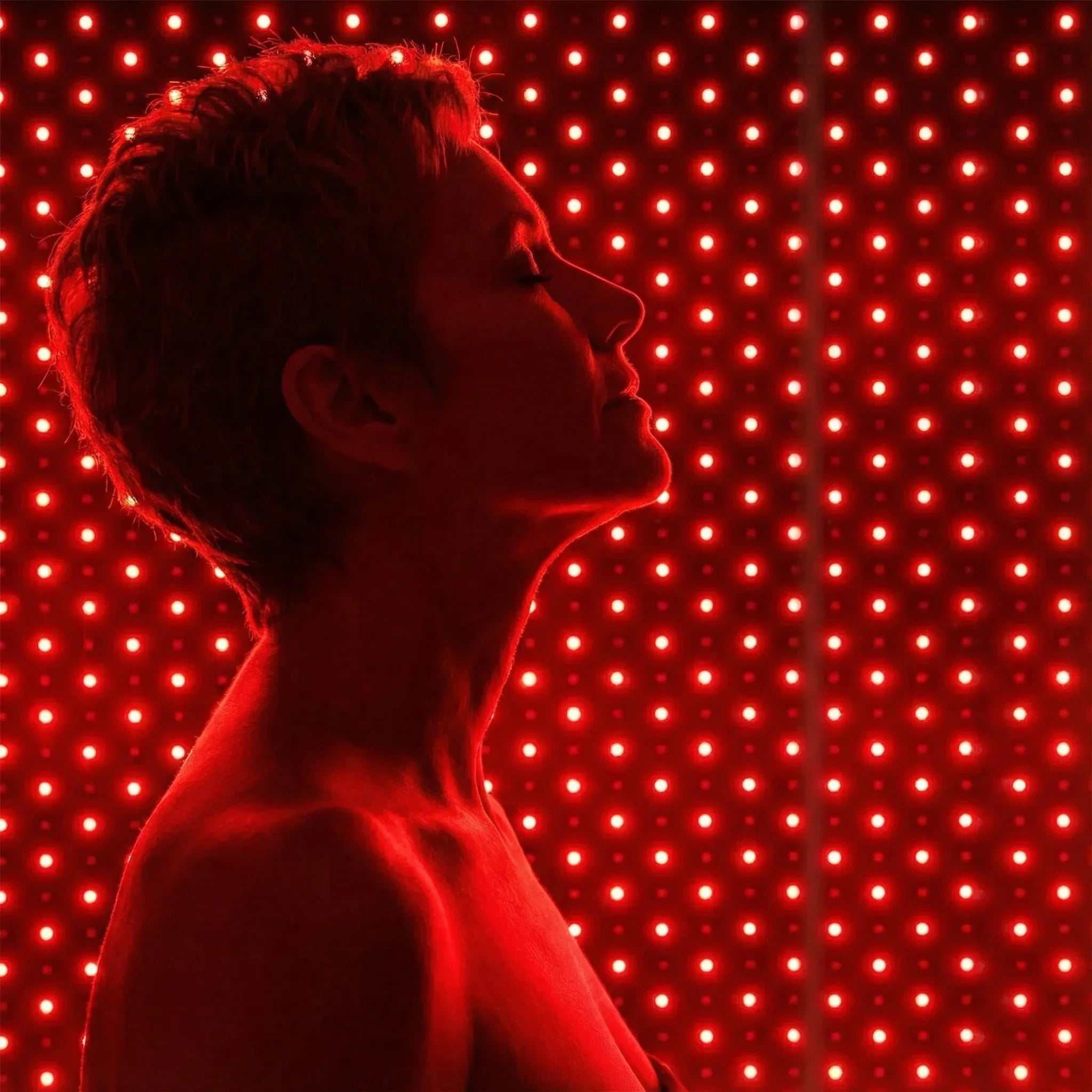 Red Light Therapy Mat with a woman in profile illuminated by red light from a dense LED panel