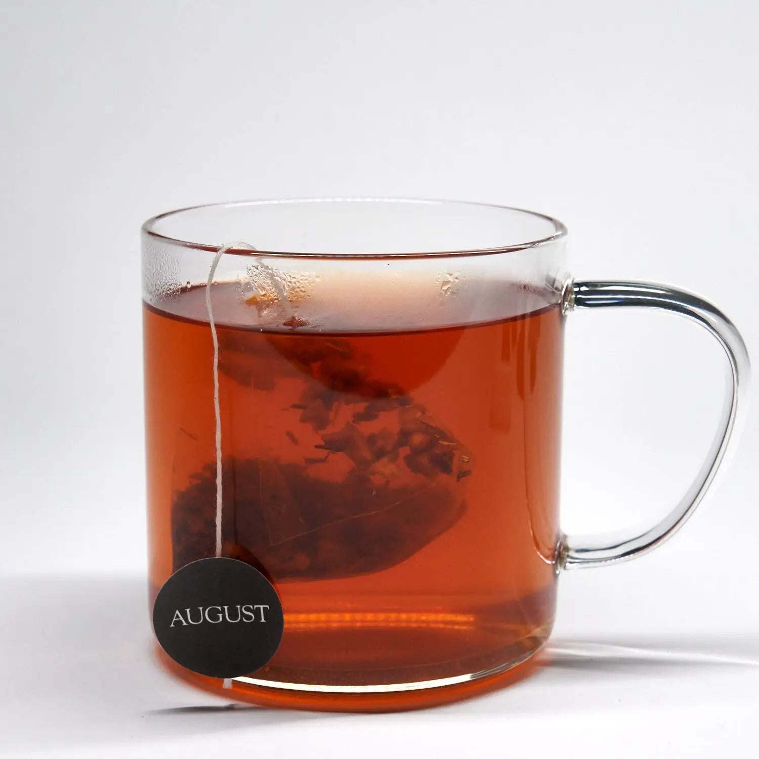 Roasted Pumpkin Caramel Rooibos Tea in a clear glass mug, deep amber brew with a visible tea sachet and tag.